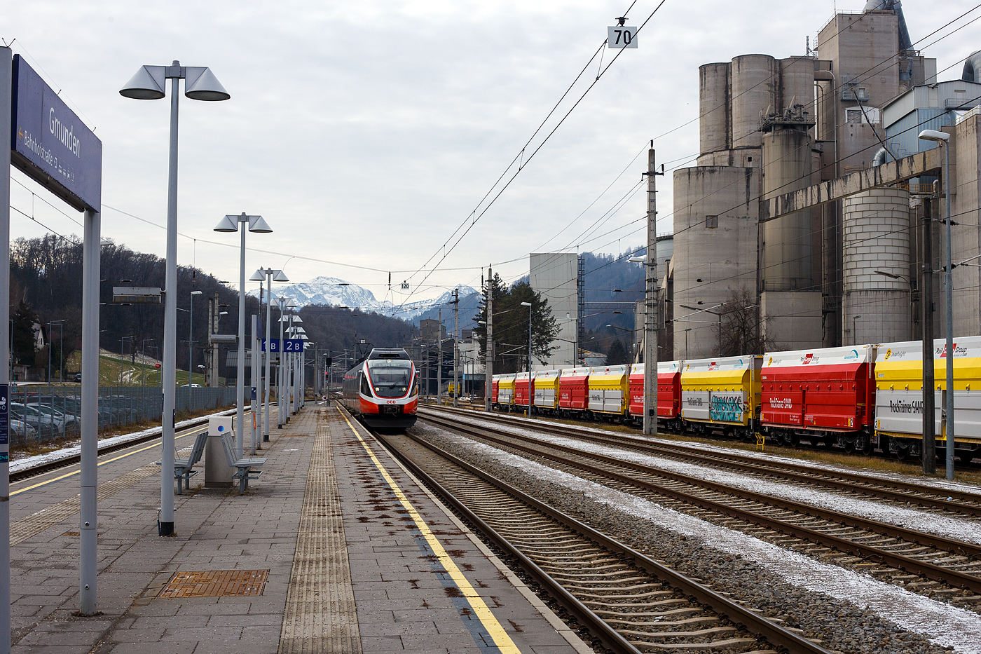 Der ÖBB 4024 023-5, ein vierteiliger elektrischer TALENT, erreicht am 14 Januar 2025, als REX 70 (4409) nach Linz Hbf über Attnang-Puchheim, den Bahnhof Gmunden. Rechts das Zementwerk Hatschek in Gmunden der Rohrdorfer Zement GmbH.