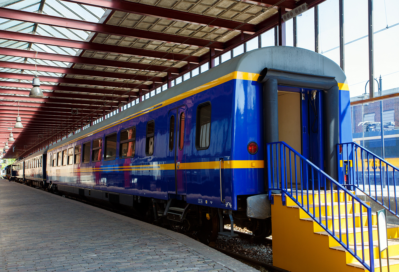 Der Personenwagen NL-NS 61 84 89-70 003-8 (Sr 10) Salonwagen Königin Beatrix vom königlichen Zug „Koninklijke Trein“ (Hofzug) am 29 April 2025 im Het Spoorwegmuseum (bis 2005 NSM - Nederlands Spoorwegmuseum / Niederländischen Eisenbahnmuseum) in Utrecht im ehemaligen Bahnhof Maliebaan. Sr steht für Salonrijtuig in Deutsch Salonwagen.

Der Wagen wurde 1980 von der Waggonfabrik Talbot GmbH & Co. in Aachen (D) gebaut und als ICR-Wagen (Intercityrijtuig), vom Type A10 ICR-1-A, an die NS - Nederlandse Spoorwegen (Niederländische Eisenbahnen) geliefert, wo er die Nummer NL-NS 50 84 10-70 647-9 trug. 1991 gab das Ministerium für Verkehr, öffentliche Arbeiten und Wasserwirtschaft einen neuen königlichen Zug für Königin Beatrix in Auftrag, da die alten Waggons nicht mehr ausreichten. Man entschied sich für den Umbau eines bestehenden Intercity-Waggons. NS Design war gemeinsam mit der Königin für die Innenausstattung verantwortlich.

Königin Beatrix hatte einen klaren Wunsch: Der Zug sollte „schick und schlicht italienisch“ sein. Das Ergebnis war ein funktionales Interieur mit luxuriösen Materialien wie Marmor, warmem rotem Leder und Birnbaumholz. Der SR10 war zudem der erste königliche Waggon mit Klimaanlage sowie Warm- und Kaltwasser.

So wurde 1992 dieser Wagen zum Sr 10 umgebaut und bekam nun die Nummer NL-NS 61 84 89-70 003-8. Wie die anderen Wagen des Königlichen Zuges verfügte er über eine europäische Zulassung. Im Inland wurden sie als Sonderzüge eingesetzt, im Ausland jedoch an reguläre D-Züge gekoppelt. Der SR10 wurde erstmals im Februar 1994 für eine Reise der königlichen Familie nach Österreich eingesetzt.

Der SR10 verfügt über eine Lounge mit einem Besprechungs-/Esstisch und einer Sitzecke mit vier Sesseln und einem Sofa. Es gibt drei Schlafbereiche, zwei für die königliche Familie und einen für die Zugführer. Die Schlafzimmer der königlichen Familie verfügen jeweils über ein eigenes Bad, einen Arbeitsbereich mit Schreibtisch und ein Etagenbett für zwei Personen. Später wurde der Zug auch von König Willem-Alexander genutzt. Ein Schlafzimmer wurde daraufhin umgebaut, um ein drittes Bett für die Prinzessinnen unterzubringen.

Im Juni 2023 reiste der königliche Wagen zu einem Staatsbesuch nach Belgien, dies war sein letzter Einsatz als königlicher Wagen. Der Wagen wurde zu einem späteren Zeitpunkt dem Eisenbahnmuseum übergeben. Der SR10 im Eisenbahnmuseum markiert das Ende von 185 Jahren königlicher Zug „Koninklijke Trein“ (Hofzug). Bereits 1839 wurde ein Sonderwaggon für die königliche Familie in Betrieb genommen, später folgten Luxuswaggons für König Wilhelm II. und III. 1864 wurde ein spezieller Waggon für Königinmutter Anna Paulowna gebaut, der SR1. 

Alle königlichen Züge der Sammlung – der SR1, der SR8 und der SR9 – die Waggons für Königin Juliana und Prinz Bernhard – sowie der SR10 – sind auf dem Bahnsteig von Utrecht Maliebaan ausgestellt.

TECHNISCHE DATEN:
Spurweite: 1.435 mm (Normalspur)
Achsfolge: 2'2'
Länge über Puffer: 26.400 mm
Wagenkastenlänge: 26.100 mm
Wagenkastenbreite: 2.820 mm
Höhe über Schienenoberkante: 3.930 mm
Drehzapfenabstand: 19.000 mm
Achsabstand im Drehgestell: 2.560 mm
Leergewicht: 47 t
Höchstgeschwindigkeit: 160 km/h
Bremse: O-R-A (D)

Die Intercity-Wagen (ICR):
Der NS Intercity-Wagen (ICR) ist ein Wagen, der seit 1980 von der Niederländischen Eisenbahn (NS) in Intercity-Zügen eingesetzt wird.

Entwicklung:
Die Wagen wurden aus dem Mittelteil des Intercity-Triebzuges ICM („Koploper“) entwickelt. Sie sind mit Y32-Drehgestellen ausgestattet, die in den 1970er Jahren für die französischen Corail-Wagen entwickelt wurden und für die damalige Zeit beispiellos gute Fahreigenschaften aufwiesen. Zwischen 1978 und 1984 wurden mehrere Corail-Waggons von der SNCF gemietet. Es wurde daraufhin überlegt, für die gezogenen Züge Wagen dieses Typs anzuschaffen. Stattdessen entschied man sich, den ICR als eigenen Wagen zu entwickeln, allerdings mit den französischen Drehgestellen. Die Gestaltung des Innenraums wurde von den Corail-Waggons beeinflusst. Die ursprüngliche Innenausstattung der ICR-Wagen wurde später auch in den ICM-Triebzügen verwendet.

Technik:
ICR wurde von der Firma Talbot in Aachen gebaut. Die Wagen sind 26,4 Meter lang und ruhen auf zwei zweiachsigen Y32-Drehgestellen, die mit Schraubenfedern gefedert und mit einer kombinierten Scheiben-/Klotzbremse gebremst werden. Die Wagenheizung erfolgt elektrisch. Im Gegensatz zu älteren Waggons, bei denen die Niederspannung über Achsgeneratoren erzeugt wurde, bezieht ICR die Niederspannung für Beleuchtung und Belüftung über einen Stromrichter und Wechselrichter aus der Zugsammelschiene (Heizleitung). Die Wagen verfügen über Schwingtüren und Schiebetüren, die nach älteren europäischen Standards durch Anheben einer Klappe an der Tür geöffnet wurden. Dies funktioniert nun wie bei anderen Zügen per Knopfdruck. Die 
Höchstgeschwindigkeit der Wagen beträgt 160 km/h.
