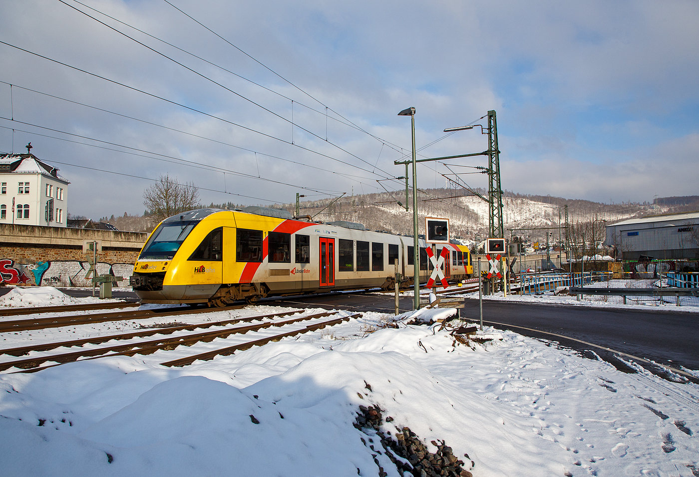 Der VT 252 (95 80 0648 152-6 D-HEB / 95 80 0648 652-5 D-HEB) ein Alstom Coradia LINT 41 der HLB (Hessische Landesbahn), hat am 21.01.2023, als RB 90 (Umlauf 61714)  Westerwald-Sieg-Bahn  (Westerburg – Altenkirchen - Au/Sieg - Siegen), Niederschelden (eigentlich Niederschelderhütte) verlassen und fährt hier beim Bü 343, km 112,183 nun weiter in Richtung Siegen. 