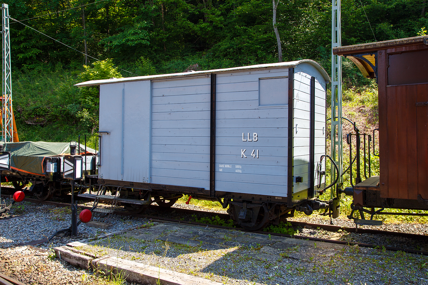 Der zweiachsige gedeckte Güterwagen mit einer Bremserbühne ex LLB K 41 der Museumsbahn Blonay-Chamby steht am 27.05.2023 im Museumsareal Chaulin. 

Der Wagen wurde 1915 von der SWS in Schlieren (Schweizerische Wagons- und Aufzügefabrik AG) gebaut und an die 1915 eröffnete LLB geliefert. Die Leuk-Leukerbad-Bahn, abgekürzt LLB, französisch Chemin de fer Loèche-Loèche-les-Bains, betrieb zwischen 1915 und 1967 eine 10,4 Kilometer lange, elektrifizierte und schmalspurige Zahnradbahnstrecke im schweizerischen Kanton Wallis. Nach der Stilllegung der Strecke 1967 wurde der Wagen von der gerade gegründeten Museumsbahn Blonay–Chamby (ursprünglich Société pour la création du chemin de fer touristique Blonay–Chamby) übernommen.

TECHNISCHE DATEN:
Spurweite: 1.000 mm (Meterspur)
Achsanzahl: 2
Länge über Puffer: 5.800 mm
Breite: 2.100 mm
Achsabstand: 2.700 mm
Laufraddurchmesser: 660 mm (neu)
Bremszahnrad-Teilkreis: Ø 496,8 mm (ursprünglich)
Eigengewicht: 4.470 kg
Nutzlast: 5.000 kg