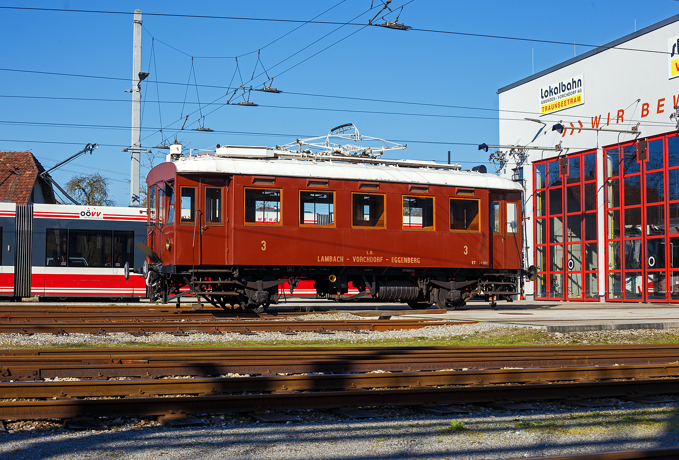 Der zweiachsige historische Normalspur 3 Klasse Elektrotriebwagen ET 24.101, ex ET 24.001, der Lokalbahn Lambach – Vorchdorf-Eggenberg (der Stern & Hafferl Verkehrsgesellschaft m.b.H.) steht am 04 April 2025 vor der Remise der Stern & Hafferl beim Bahnhof Vorchdorf-Eggenberg. Nach der Nummerierung „24“ war dieser Triebwagen urspr�nglich der bis 2009 stillgelegten Lokalbahn Lambach–Haag am Hausruck zugeordnet. 

Den pr�chtig restaurierten Triebwagen lieferte 1931 die Grazer Waggonfabrik und Siemens-Schuckert Wien gemeinsam mit einem zweiten typengleichen Triebwagen anl�sslich der Elektrifizierung der Vorchdorferbahn. Die beiden einfachen aber durchaus zweckm��ig gehaltenen Triebwagen gab es zum Preis von je �S 77.500.- (nach heutigem Geldwert ca. Euro 300.000.-).

Der Wagenkasten besteht aus Eichenholz mit gro�en Fenstern und Blechverkleidung. Die Innenausstattung wurde durch Verwendung verschiedener H�lzer ansprechend gestaltet. Die Dachdeckung besteht aus impr�gnierter Segelleinwand. Die Triebwagen verf�gen �ber einen Fassungsraum von 46 Sitz- und 18 Stehpl�tzen. Das Dienstgewicht betr�gt 17,3 Tonnen. Der Wagen hat eine L�nge �ber Puffer von 11,00 m und einen Radstand von 5,5 m. Die elektrische Ausr�stung besteht aus 2 Gleichstrommotoren � 53 kW, gesteuert �ber 2 Fahrschalter mit jeweils 12 Fahr- und 7 Bremsstufen. Von der elektrischen Bremse unabh�ngig, ist eine selbstt�tige Vacuum Bremse eingebaut, welche, wie auch die Handspindelbremse auf das gleiche Bremsgest�nge wirkt. Heizung und Beleuchtung erfolgen elektrisch, f�r die 1930 er Jahre bei Lokalbahnen oft noch ein unbekannter Luxus. Vom Triebwagen k�nnen auch allf�llige Personen – oder Dienstwagen mit Licht- und Heizstrom versorgt werden. Als Stromabnehmer dient ein Scherenb�gel vom Typ SBS 15, urspr�nglich mit sogenannter Fischerpalette (ein Stahlblech Pressst�ck mit Rillen in welches Schmiermittel eingef�llt wurde) ausgestattet. Nach 1946 erfolgte, nicht zuletzt um St�rungen des Rundfunks und des zunehmenden Funkverkehrs zu vermeiden, die Umstellung auf Grafit Schleifst�cke. Als Signalmittel dient ein Horn welches �ber die Abluft der Vacuum Pumpe gespeist wird und ein, einem Rind nicht un�hnliches Gebr�ll abgibt. Das f�hrte auch zum Spitznahmen „Braune Kuah“. Geliefert wurden beide Triebwagen in elegantem, aber dunklen Braun mit vornehmer Schattenschrift f�r den Eigent�mer und die Fahrzeugnummer versehen. Die beh�rdliche Abnahme beider Triebwagen erfolgte am 21. Dezember 1931. Die urspr�ngliche H�chstgeschwindigkeit von 30 km/h konnte ab 1933 auf 40 km/h angehoben werden. Gleichzeitig mit dem Einbau einer Sicherheitsfahrschaltung (Sifa) f�r den Einmannbetrieb wurde auch die zul�ssige Fahrzeugh�chstgeschwindigkeit auf 50 km/h erh�ht. �u�erlich kaum zu unterscheiden, folgten 1932/3 zwei �hnliche Triebwagen f�r die Lokalbahn Lambach – Haag am Hausruck.

Der Triebwagen 24.101 erhielt 1939 eine weinrot/beige Lackierung analog den Triebwagen der Deutsche Reichsbahn. Ab den sp�ten 1950er Jahren pr�sentierte sich der Triebwagen in der klassischen Stern&Hafferl Lackierung dieser Epoche, in braun-ockergelb.

Durch verschiedenste Umbauten bzw. auch Ausmusterungen der Triebwagenfamilie befand sich Mitte der 1980er Jahre nur mehr der Triebwagen ET 24.101 in einem weitgehend originalen, aber sch�bigen Zustand. Der Triebwagen wurde 1985/86 in der Hauptwerkst�tte Vorchdorf vorbildlich restauriert und erfreut seither Jung und Alt bei seinen Ausfahrten.
