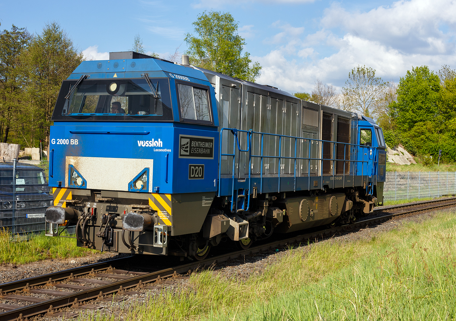 Die 272 408-6 / D20 der Bentheimer Eisenbahn AG (92 80 1272 408-6 D-BE), ex Rurtalbahn V 203 (92 80 1272 408-6 D-RTBC), eine Vossloh G 2000BB (mit symmetrischem Führerhaus) im Dienst für die KSW (Kreisbahn Siegen-Wittgenstein) auf der Talbahn, hier als Lz auf der Rückfahrt vom Pfannenberg kommend in Neunkirchen-Struthütten. Hier die KSW-Bahnstrecke Herdorf–Pfannenberg-(ehem. Unterwilden) ist eine rund 8 km lange Nebenbahn, bekannt ist sie auch als „Talbahn“. Die Strecke wurde von der 1904 gegründeten Freien Grunder Eisenbahn AG betrieben. Die gebliebenen Gleise und Anlagen sind seit 1970, als Betriebsstätte FGE - Freien Grunder Eisenbahn. Teil der heutigen Kreisbahn Siegen-Wittgenstein.

Die Lok ein Vossloh G 2000-3 BB (mit symmetrischem Führerhaus) wurde 2008 von Vossloh in Kiel unter der Fabriknummer 5001752 gebaut und als V 203
(92 80 1272 408-6 D-RTB) an die RTB - Rurtalbahn GmbH in Düren geliefert. Etwa 2019 ging sie zurück an Vossloh Locomotives GmbH und war als Mietlok unterwegs, im Juli 2021 ging sie dann an die BE - Bentheimer Eisenbahn AG (Nordhorn), wo sie nun D 20 bezeichnet wird. Die Lok hat die UIC-Zulassungen für Deutschland, die Niederlande und Belgien.

TECHNISCHE DATEN:
Achsformel: B'B'
Spurweite: 1.435 mm (Normalspur)
Länge über Puffer: 17.400 mm
Drehzapfenabstand: 9.500 mm
Achsstand im Drehgestell: 2.400 mm
Treibraddurchmesser: 	1.000 mm
Höhe: 4.220 mm
Breite: 3.080 mm
Dieselmotor: Caterpillar V-16-Viertakt-Dieselmotor mit Turboaufladung und Ladeluftkühlung vom Typ CAD 3516 B-HD
Motorleistung: 2.240 kW
Motor-Nenndrehzahl: 1800/min
Getriebe: Voith L 620 reU2
Leistungsübertragung: hydraulisch
Anfahrzugkraft: 283 kN
Dienstgewicht: 87,3 t
Höchstgeschwindigkeit: 120 km/h
Kleinster bef. Halbmesser: 80 m
Bremse: KE-GP mZ (D)
Tankinhalt: 5.000
