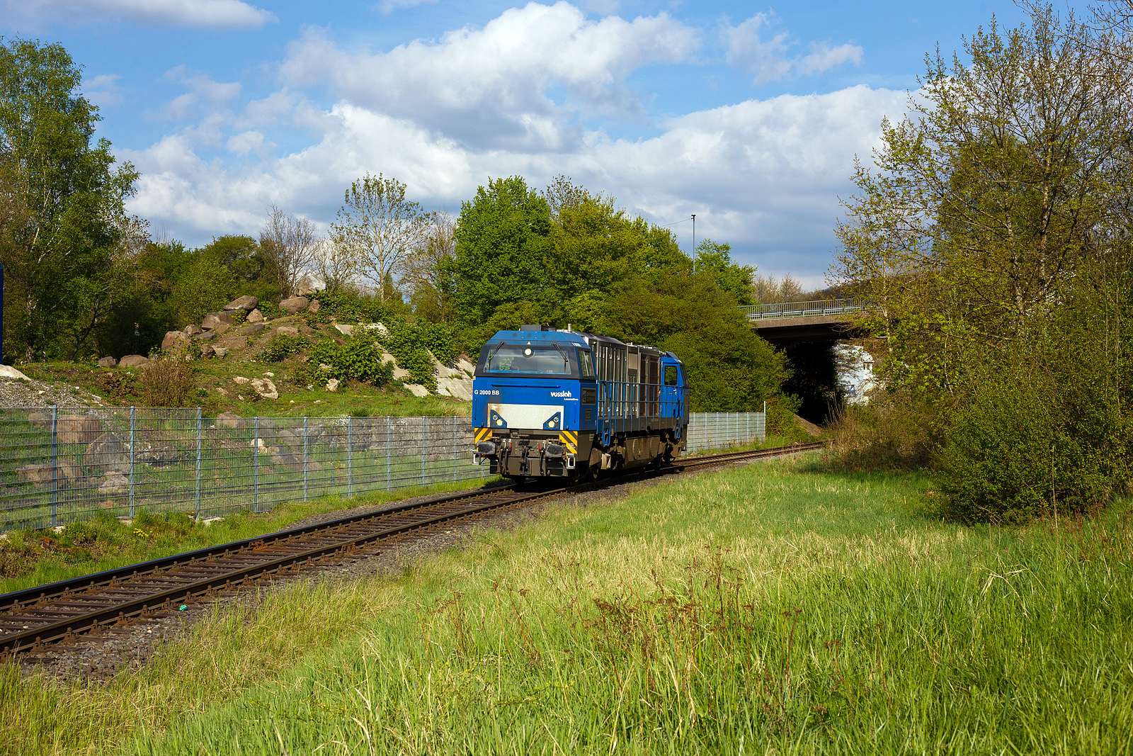 Die 272 408-6 / D20 der Bentheimer Eisenbahn AG (92 80 1272 408-6 D-BE), ex Rurtalbahn V 203 (92 80 1272 408-6 D-RTBC), eine Vossloh G 2000BB (mit symmetrischem Führerhaus) im Dienst für die KSW (Kreisbahn Siegen-Wittgenstein) auf der Talbahn, hier als Lz auf der Rückfahrt vom Pfannenberg kommend in Neunkirchen-Struthütten. Hier die KSW-Bahnstrecke Herdorf–Pfannenberg-(ehem. Unterwilden) ist eine rund 8 km lange Nebenbahn, bekannt ist sie auch als „Talbahn“. Die Strecke wurde von der 1904 gegründeten Freien Grunder Eisenbahn AG betrieben. Die gebliebenen Gleise und Anlagen sind seit 1970, als Betriebsstätte FGE - Freien Grunder Eisenbahn. Teil der heutigen Kreisbahn Siegen-Wittgenstein.

Die Lok ein Vossloh G 2000-3 BB (mit symmetrischem Führerhaus) wurde 2008 von Vossloh in Kiel unter der Fabriknummer 5001752 gebaut und als V 203
(92 80 1272 408-6 D-RTB) an die RTB - Rurtalbahn GmbH in Düren geliefert. Etwa 2019 ging sie zurück an Vossloh Locomotives GmbH und war als Mietlok unterwegs, im Juli 2021 ging sie dann an die BE - Bentheimer Eisenbahn AG (Nordhorn), wo sie nun D 20 bezeichnet wird. Die Lok hat die UIC-Zulassungen für Deutschland, die Niederlande und Belgien.

TECHNISCHE DATEN:
Achsformel: B'B'
Spurweite: 1.435 mm (Normalspur)
Länge über Puffer: 17.400 mm
Drehzapfenabstand: 9.500 mm
Achsstand im Drehgestell: 2.400 mm
Treibraddurchmesser: 	1.000 mm
Höhe: 4.220 mm
Breite: 3.080 mm
Dieselmotor: Caterpillar V-16-Viertakt-Dieselmotor mit Turboaufladung und Ladeluftkühlung vom Typ CAD 3516 B-HD
Motorleistung: 2.240 kW
Motor-Nenndrehzahl: 1800/min
Getriebe: Voith L 620 reU2
Leistungsübertragung: hydraulisch
Anfahrzugkraft: 283 kN
Dienstgewicht: 87,3 t
Höchstgeschwindigkeit: 120 km/h
Kleinster bef. Halbmesser: 80 m
Bremse: KE-GP mZ (D)
Tankinhalt: 5.000
