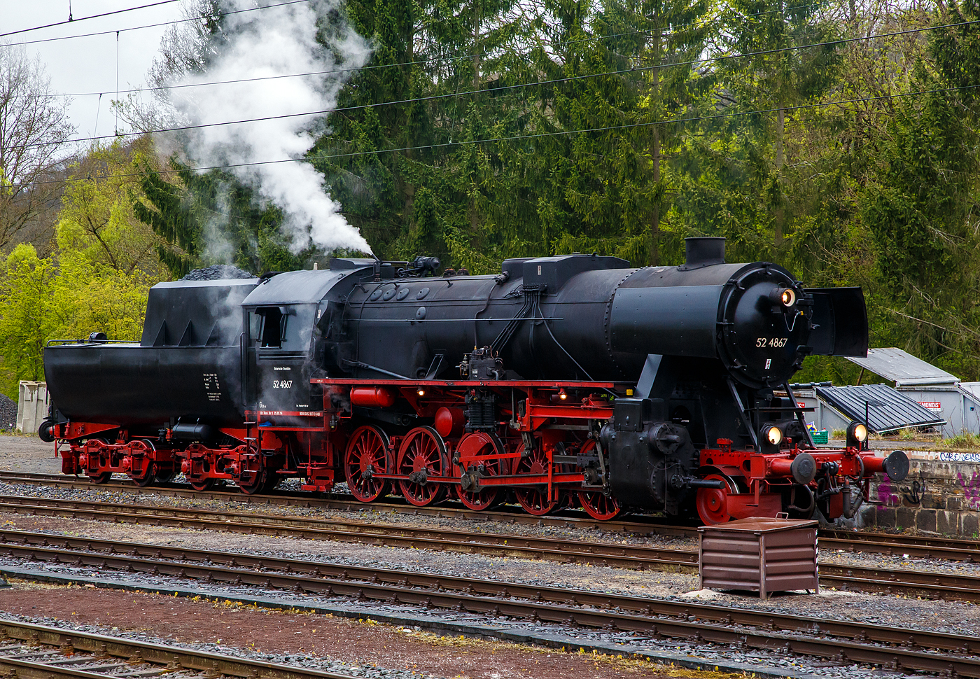 Die 52 4867 / 052 867-3 (90 80 0052 867-3 D-HEF) der Historische Eisenbahn Frankfurt e.V., ex GKB 152.4867 (Graz-Köflacher Eisenbahn- und Bergbaugesellschaft), ex ÖBB 152.4867, ex DRB 52 4867, am 22 April 2017 beim Bahnhof Au/Sieg.

Die Güterzug-Dampflokomotive 52 4867 wurde 1943 bei Maschinenbau und Bahnbedarf AG in Potsdam-Babelsberg unter der Fabriknummer 13931 gebaut und an die Deutschen Reichsbahn geliefert. Nach dem Krieg blieb sie in Österreich und wurde zur ÖBB 152.4867, 1970 kam sie zur GKB und 1980 kaufte die HEF die Lok.

So ist diese Lok noch eine Ur-52er (also keine Roko-Lok) mit Barrenrahmen. Barrenrahmen, wie sonst allgemein bei der Deutschen Reichsbahn üblich, wurden von den Lokomotivfabriken bei den ersten Lieferungen der Baureihe 52 noch eingebaut. Dies aber nur solange wie noch vorgefertigte Rahmen, für die zugunsten der BR 52 eingestellte Produktion, der in den Abmessungen identischen Baureihe 50, lagerte. Später wurden sie mit geschweißtem Blechrahmen gefertigt.

In Österreich befanden sich nach Kriegsende über 700 Lokomotiven, von denen nach Ausmusterungen, Rückgaben, Tauschen und Beschlagnahmen 1953 letztlich noch 313 für die Umzeichnung auf den neuen ÖBB-Nummernplan übrigblieben, die bei den Österreichischen Bundesbahnen unter Beibehaltung der Nummerierung als Reihe 52 eingereiht wurden, aber nach österreichischer Tradition mit einem Punkt zwischen Stamm- und Ordnungsnummer. Die 37 Maschinen der BR 52, die auf einem Barrenrahmen aufgebaut waren, erhielten die Reihenbezeichnung 152 (eine „1“ vor die 52). Die GKB hatte zwischen 1968 und 1973 13 Barrenrahmenlokomotiven der Baureihe 152 gekauft. Zu ihnen zählte auch diese 52 4867, die nach ihrer Ausmusterung wieder nach Deutschland gelangte.