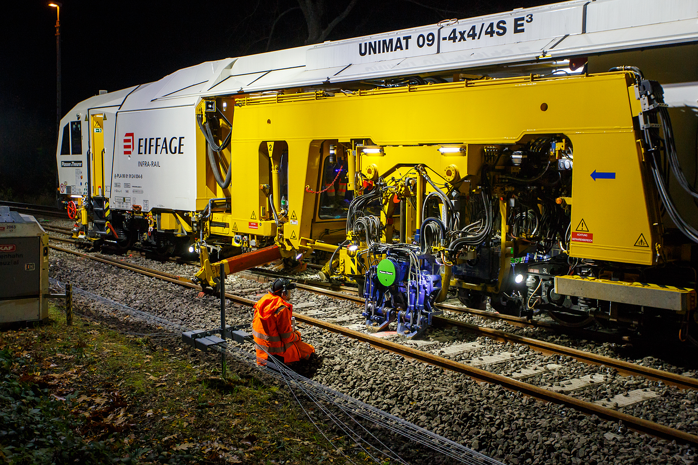 Die Baustelle Bahnhof Herdorf am Abend des 26 Oktober 2025, nun ab 20:40 Uhr wird die neue Weiche 3, beim Bahnhof/Stellwerk Herdorf Fahrdienstleiter (Hf), gestopft. Hier kam die recht neue Plasser & Theurer UNIMAT 09-4x4/4S E� (A-PLA 99 81 9124 004-8), eine Universal-Weichenstopfmaschine mit Hybrid-Antriebstechnik, der Firma Eiffage Infra-Rail GmbH (Herne) zum Einsatz. Ob die Maschine nur von Eiffage Infra-Rail gemietet oder nun gekaut wurde ist mir nicht klar, aber eingestellt ist sie in �sterreich �ber Franz Plasser Vermietung von Bahnbaumaschinen GmbH.

Detailbild vom Stopfvorgang, hier kann am auch gut erkennen was u.a. eine Weichenstopfmaschine ausmacht, die Stopfpickel sind u.a. seitlich verschiebbar. 