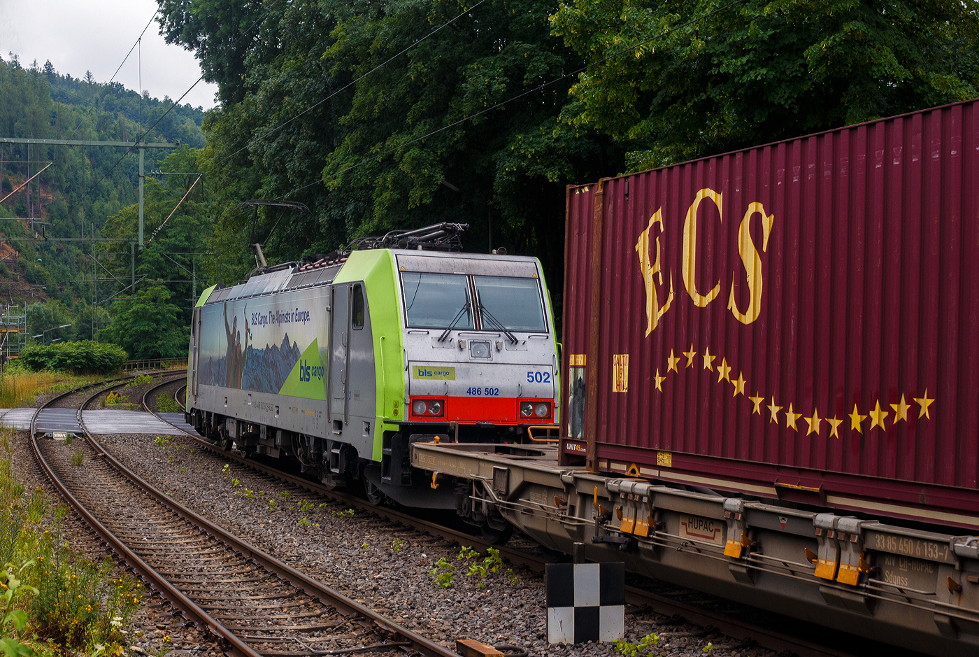 Die BLS Cargo 502, Re 486 502-8/E 486 502 SF  The Alpinists in Europa  (91 85 4486 502-8CH-BLSC) f�hrt am 07 Juli 2025 mit einem HUPAC KLV-Zug durch Kirchen (Sieg) in Richtung K�ln.

Nochmals einen lieben Gru� an den netten Lokf�hrer zur�ck.

Die TRAXX F140 MS wurde 2008 von Bombardier in Kassel unter der Fabriknummer 34401 gebaut und an die BLS Cargo AG (Bern) geliefert. Die Loks sind nur f�r die Schweiz, Deutschland, �sterreich und Italien zugelassen.

Der Erfolg im G�terverkehr veranlasste die BLS zehn weitere TRAXX zu bestellen im Gegensatz zur ersten Serie TRAXX F140 AC1 mit der Bezeichnung Re 485 001 bis 485 020, die nur unter Wechselstrom fahren k�nnen, k�nnen die TRAXX F140 MS Re 486 501 bis 486 510 auch unter 3.000 Volt Gleichstrom eingesetzt werden. Bombardier hatte seit der ersten Lieferung Verbesserungen vorgenommen. Dabei wurde der Lokomotivkasten optimiert und die Traktionsausr�stung mit moderneren Komponenten versehen. Eine Nachbeschaffung w�re noch m�glich gewesen, h�tte aber dazu gef�hrt, dass die Lokomotiven nicht auf dem neuesten Stand waren und nicht unter der Gleichstromfahrleitung eingesetzt werden konnten. Die eingebauten Zugbeeinflussungssysteme erlauben den Einsatz in Deutschland, �sterreich, der Schweiz und Italien (DACHI). Anf�nglich waren die Lokomotiven in der Schweiz nur f�r den Einsatz auf Strecken mit konventioneller Zugbeinflussung und nicht auf ETCS Level 2 Strecken zugelassen. Die Re 486 k�nnen unter sich und mit den Re 485 und Lokomotiven der Baureihe 185/186 in Vielfachsteuerung eingesetzt werden. Mittlerweile nach Umbauten durch die BLS, k�nnen die Loks nun auch mit Re 465, sowie mit Siemens Vectron der BR 193 bzw. Re 475 in Mehrfachtraktion gefahren werden.

TECHNISCHE DATEN:
Spurweite: 1.435 mm (Normalspur)
Achsformel: Bo’Bo’
L�nge �ber Puffer: 18.900 mm
H�he: 4.385 mm
Breite: 2.978 mm
Drehzapfenabstand: 10.400 mm
Achsabstand im Drehgestell: 2.600 mm
Dienstmasse: 85 t
H�chstgeschwindigkeit:  140 km/h
Dauerleistung: 5.600 kW
Dauerzugkraft: 300 kN
Treibraddurchmesser: 1.250 mm
Stromsysteme: 15 kV 16,7 Hz, 25 kV 50 Hz Wechselstrom sowie 3 kV und 1,5 kV Gleichstrom
Antrieb: Tatzlager