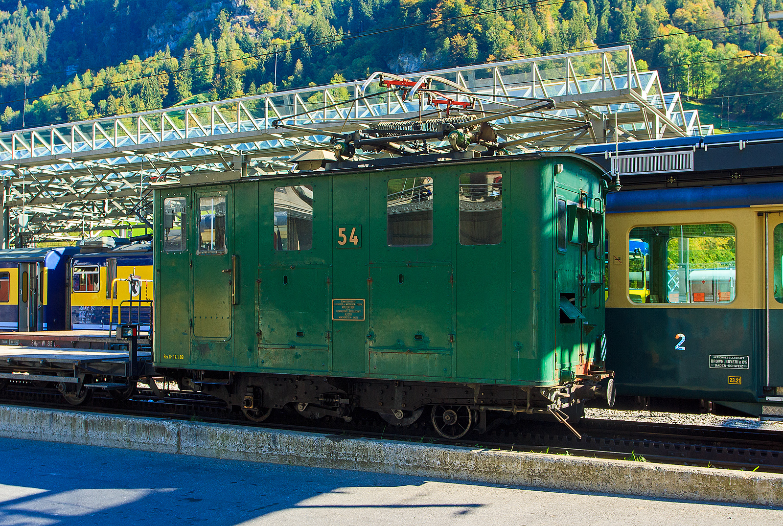 Die elektrische Zahnradlokomotive WAB He 2/2 - 54 am 02.10.2011 abgestellt im Bahnhof Lauterbrunnen.

Die Gleichstrom-Elektro-Zahnradlokomotive wurde 1909 von der Schweizerischen Lokomotiv- und Maschinenfabrik (SLM) in Winterthur unter der Fabriknummer 1955 gebaut, der elektrische Teil ist von Alioth.

Die He 2/2 51 bis 58 der Wengernalpbahn (WAB) sind elektrische Zahnradlokomotiven für Gleichspannung von 1.500 Volt und einer Spurweite von 800 mm, die in den Jahren 1909 und 1910 anlässlich der Elektrifikation der Bahn in Betrieb gesetzt wurden. Sie dienten als Vorbild für die weitgehend baugleichen Nachfolger He 2/2 59 bis 63.

Bei den Maschinen mit zwei Laufachsen und zwei Triebzahnrädern handelt es sich um reine Zahnradlokomotiven. Die beiden Triebzahnräder, für das Zahnstangensystem Riggenbach-Pauli und Von Roll, sind nicht auf den Laufachsen angebracht, sondern unmittelbar neben der Laufachsen gegen die Fahrzeugmitte. Der mechanische Teil stammt von der Schweizerischen Lokomotiv- und Maschinenfabrik (SLM) in Winterthur, die elektrische Ausrüstung erhielten die Lokomotiven durch die Elektrizitätsgesellschaft Alioth (EAG), umgangssprachlich Alioth, in Münchenstein. Für die Talfahrt haben die Lokomotiven als Beharrungsbremse eine selbsterregte elektrische Widerstandsbremse, die eine Talfahrt mit gesenktem Stromabnehmer ermöglicht.

Charakteristisch für die langlebigen Maschinen ist der kantige Lokomotivkasten mit den beidseitigen bullaugenförmigen runden Maschinenraumfenstern die mit Deckleisten und einem mächtigen Stromabnehmer mit zwei Schleifstücken, der mit damaligen wie auch heutigen Pantografen wenig gemeinsam hat. Erst in den 1960er und der ersten Hälfte der 1970er Jahre erhielten die Lokomotiven Pantografen üblicher Bauart.

Die 5.740 mm langen Lokomotiven mit einem Dienstgewicht von rund 16 t verkehren mit ihren 300 PS auf Neigungen bis zu 250 ‰ in der Regel mit zwei Vorstellwagen, auf Steigungen bis rund 190 ‰ in der Regel mit drei Vorstellwagen. Sie erreichen dabei bei der Bergfahrt eine Geschwindigkeit von rund 10 bis 11 km/h, abhängig von der Belastung und der effektiven Fahrdrahtspannung. Bei der Talfahrt ist die Geschwindigkeit aus Sicherheitsgründen auf maximal 12 km/h limitiert.

Mehrere Lokomotiven aus dieser Serie wurden ab den 1960er Jahren erst in der Sommersaison an die Schynige Platte-Bahn (SPB) vermietet und dann verkauft. Die Lokomotive He 2/2 55 ist als Museumslokomotive auf dem frei zugänglichen Aussenareal der Primeo Energie, ehemals Elektra Birseck, in Münchenstein erhalten geblieben. Die Lokomotive He 2/2 56 ist als He 2/2 16 Anemone bei der Schynige Platte-Bahn in roter Farbgebung betriebsfähig erhalten geblieben. Die Lokomotive He 2/2 58 ist als He 2/2 18 Krokus, dann Gündlischwand, bei der Schynige Platte-Bahn in brauner Farbgebung betriebsfähig erhalten geblieben.

TECHNISCH DATEN:
Baujahre: 1909 und 1910
Nummerierung: 	51–58
Spurweite: 800 mm
Zahnradsystem: 	Riggenbach-Pauli
Länge über Puffer : 5.740 mm
Achsstand: 2.600 mm
Zahnradteilkreis-Ø: 700 mm
Laufraddurchmesser: 525 mm (neu)
Dienstgewicht: 16 t
Leistung: 2 x 110 kW
Zul. Höchstgeschwindigkeit: 12 km/h
Übersetzung:  1:11,6
Stromsystem: 1500 V DC
Beharrungsbremse: elektrisch
Max. Neigung : 250 ‰

Die Wengernalpbahn, kurz WAB, ist eine 1893 eröffnete schmalspurige Zahnradbahn  im Berner Oberland, mit einer Spurweite von 800 mm und dem Zahnstangensystem Riggenbach-Pauli. Sie führt von Lauterbrunnen über Wengen und die Kleine Scheidegg nach Grindelwald. Benannt wurde sie nach der Wengernalp, die sich zwischen Wengen und der Kleinen Scheidegg befindet. Mit einer Länge von 19,114 km gilt sie als längste durchgehende Zahnradbahn der Welt.
