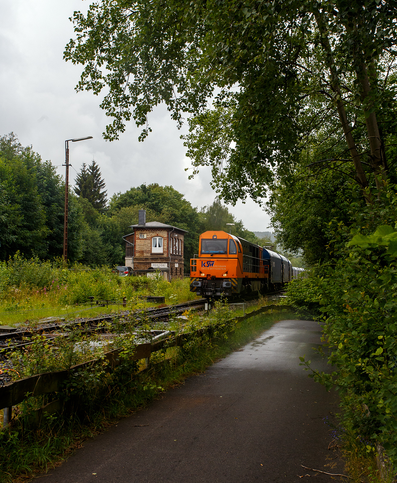 Die KSW 43 (92 80 1273 018-2 D-KSW), die asymmetrische Vossloh G 2000 BB der KSW (Kreisbahn Siegen-Wittgenstein) fährt am 03 Juli 2024, nun mit dem beladen Coilzug (16 Stück VTG Coilwagen der Gattung Shimmns-ttu, VTG Bez. F46.520D) vom Bahnhof Herdorf auf den Rbf der KSW (Betriebsstätte FGE -Freien Grunder Eisenbahn).