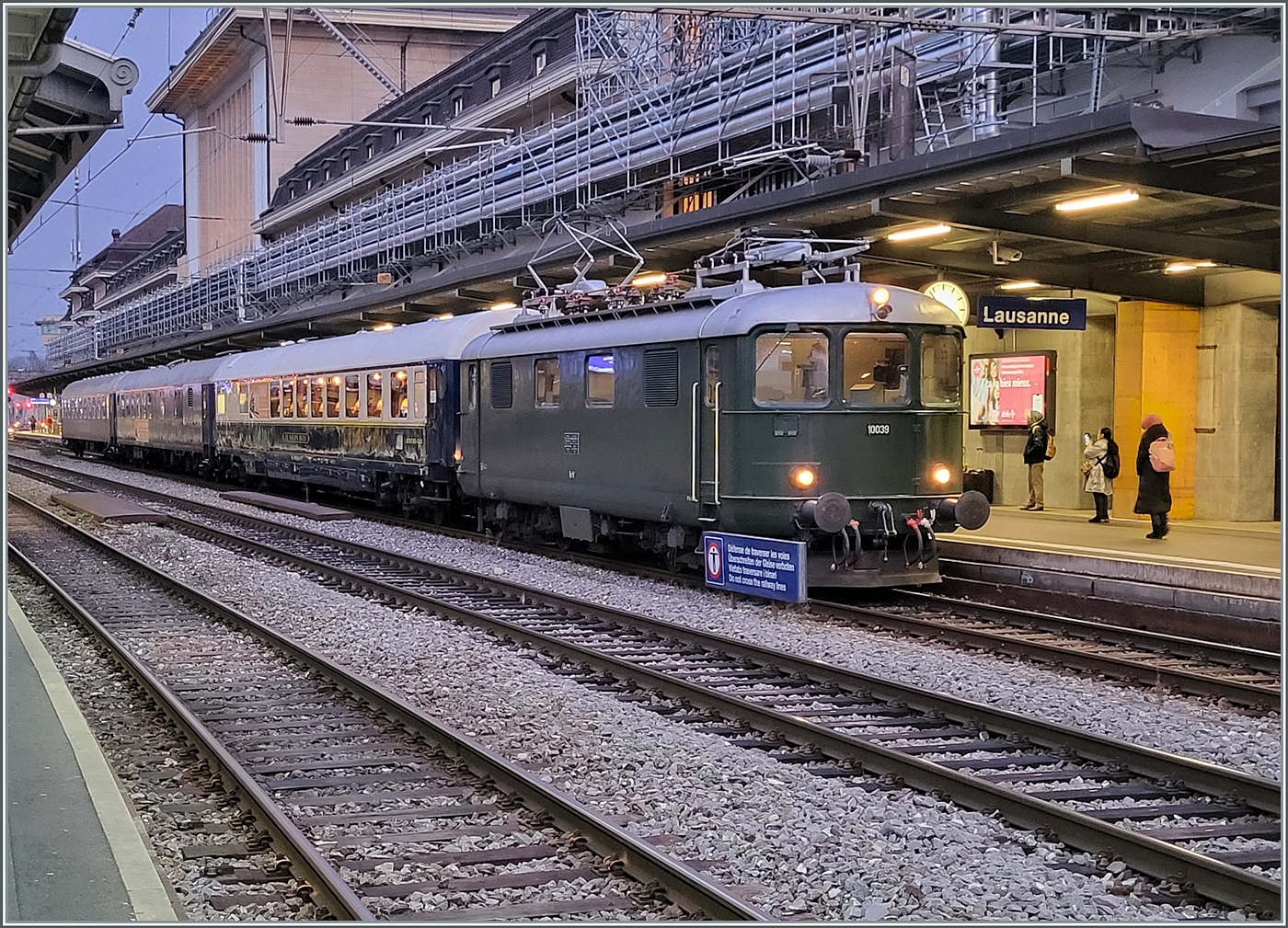 Die Re 4/4 I 10039 stellt den Extrazug 31131 in Lausanne bereit. Der Zug verkehrt für eine Reisegruppe nach Zürich Enge (mit Halt in Palézieux). Der Zug besteht aus dem  Le Salon Bleu  61 85 80-90 200-6 CH-IRSI, dem 56 80 89-80 010-2 WGm D-IRSI und dem Am 56 80 10-40 360-4 D-IRSI. Da der TEE Rheingold Genève - Amsterdam am Schluss seiner Einsatzzeit vor vielen Jahren aus einem DB Speisewagen, einem DB Abteilwagen und einen DB Großraumwagen bestand und auch von einer Re 4/4 I gezogen wurde, weckt der heutige Zug doch Erinnerungen an den TEE 6 / 7, der am 23. Mai 1982 zum letzten Mal ab Genève fuhr, (und sich dann noch gut zwei Jahre auf dem Abschnitt Basel - Amsterdam hielt). Leider die Re 4/4 I 10039 etwas ungeschickt vor dem Schild  Überschreiten der Geleise verboten, und leider waren diese Lichtverhältnisse nichts für meine kleine Knipse, so dass ich hier ausnahmsweise ein Handy-Bild zeige. 
Die Re 4/4 I gehört heute der SWISS RAIL TRAFFIC und war früher als Re 416 628 bei der Mittelthurgaubahn unterwegs und vorgängig bei den SBB mit der heute noch angeschrieben Nummer 10039 im Einsatz. Damals trug die am 22. Dez. 1950 abgelieferte Lok jedoch noch die verchromten Buchstaben SBB - CFF resp. SBB - FFS an den Seitenwänden.

11. Dezember 2024