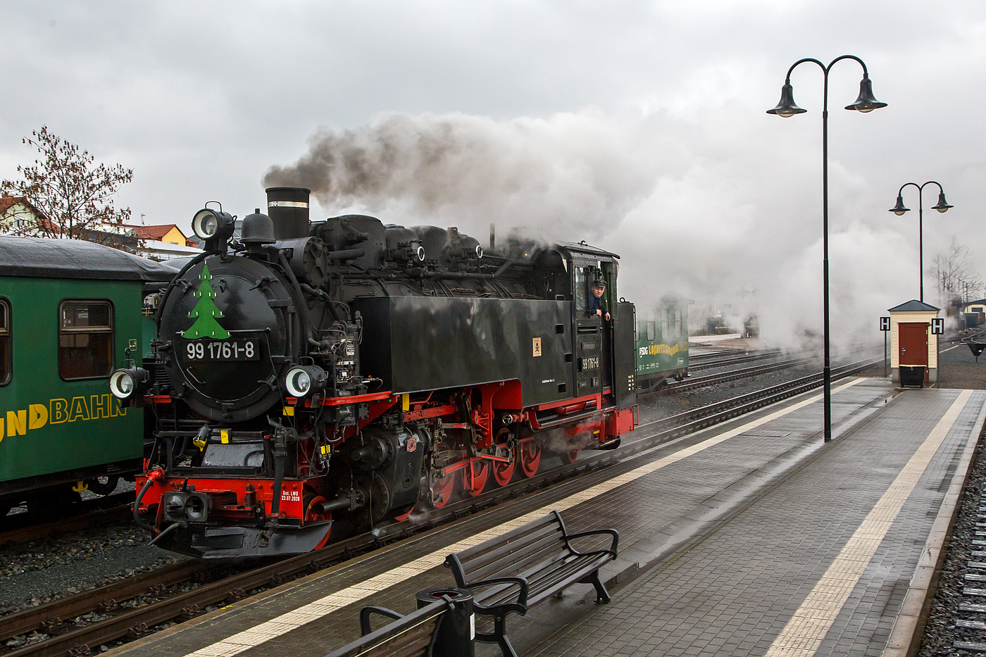 Die sächsische VII K (Altbau) Dampflok 99 1761-6 rangiert am 07 Dezember 2022 im Schmalspur-Bahnhof Radebeul Ost, um sich gleich vor, unseren Zug, den Lößnitzdackel (Lößnitzgrundbahn) für die Abfahrt in Richtung Moritzburg, zusetzen. 

Die 750 mm-schmalspurige Dampflok der Altbau-Baureihe 99.73-76 wurde 1933 von der BMAG - Berliner Maschinenbau-Actien-Gesellschaft vormals L. Schwartzkopff in Berlin unter der Fabriknummer 10152 gebaut und als 99 761an die DRG - Deutsche Reichsbahn-Gesellschaft geliefert.

Weitere Lebenslauf und Nummerierungen:
1933 bis 1970 - DRG / DRB / DR 99 761 
1970-1992 - DR 99 1761-8 
1992-1994 - DR 099 734-6 
1994-2004 - DB 099 734-6 
2004-2007 - BVO 99 1761-8 (Busverkehr Ober- und Westerzgebirge Bahn GmbH)
seit 2007- SDG 99 1761-8 (Sächsische Dampfeisenbahn Gesellschaft mbH)
Im Jahr 1964 bekam sie im Raw Cottbus einen Neubaukessel (Baujahr 1964, Fabriknummer 15).

Die 5-fach-gekuppelten Lokomotiven der Baureihe 99.73–76 waren Einheitslokomotiven der Gattung K 57.9  der Deutschen Reichsbahn für die sächsischen Schmalspurbahnen. Zusammen mit der Nachfolgebauart Baureihe 99.77–79 stellen die Lokomotiven die stärksten Schmalspurlokomotiven für 750 mm-Spurweite in Deutschland dar.

Obwohl mit der fünffach gekuppelten Baureihe 99.67–71 schon eine recht leistungsfähige Lokomotive für den Betrieb auf den Gebirgsstrecken im Erzgebirge vorhanden war, bestand auch weiterhin Bedarf an einer besonders leistungsstarken Bauart. So gelang es der neu gegründeten Reichsbahndirektion Dresden, die Beschaffung einer Einheitslokomotive für 750 mm-Spur durchzusetzen. Das Vereinheitlichungsbüro der Deutschen Lokomotiv-Vereinigung in Berlin-Tegel erarbeitete den Entwurf für die Konstruktion.

Die erste Serie von 13 Lokomotiven fertigte die Sächsische Maschinenfabrik vormals Richard Hartmann in Chemnitz. Laut Liefervereinbarung sollte die Sächsische Maschinenfabrik noch weitere Loks liefern, durch den Konkurs und die Liquidation des Unternehmens 1930 ging dieser Auftrag an die Berliner Maschinenbau AG vormals Schwartzkopff (BMAG) über. 1928 wurden sieben und 1933 noch weitere zwölf Lokomotiven von der BMAG geliefert. Die damals hochmodernen Lokomotiven entsprachen in ihrer Konstruktion den regelspurigen Einheitslokomotiven. Die Lokomotiven erfüllten die Erwartungen. Mit Vorspann war es nun möglich, auch überlange Schmalspurzüge mit bis zu 56 Achsen bergwärts zu befördern.

1945 mussten zehn Lokomotiven als Reparationsleistung an die Sowjetunion abgegeben werden. Zudem erhielten die Loks dort auch einige, bauliche Änderungen. Die hintere Laufachse wurde entfernt, und sie wurden alle auf Ölfeuerung umgebaut und mit Schlepptendern ausgerüstet. Zwischen 1975 und 1979 wurden alle Maschinen der UdSSR ausgemustert. Es waren die Loks 733, 736, 737, 744, 748, 751, 752, 753, 755 und 756. Demgegenüber stand eine enorme Zunahme der Verkehrsleistung auf den Schmalspurbahnen im Erzgebirge durch den neu aufgenommenen Uran-Bergbau der SDAG Wismut. Um dem daraus resultierenden Lokomotivmangel abzuhelfen, entstand ab 1952 eine ähnliche Nachfolgebauart beim VEB Lokomotivbau Karl Marx in Babelsberg als Baureihe 99.77–79.

Ende der 1960er Jahre mussten wegen Schäden an den Kesseln die ersten Lokomotiven ausgemustert werden. Zehn Lokomotiven erhielten neue, geschweißte Kessel und wurden auch weiterhin auf ihren Stammstrecken eingesetzt. Die 99 1760 wurde 1992 auf Ölhauptfeuerung umgebaut.

Technische Merkmale:
Die fünffach gekuppelten Lokomotiven haben einen Barrenrahmen und verfügen über in Bisselgestellen gelagerte Laufachsen. Als Treibachse dient die fest gelagerte dritte Achse, welche anfangs geschwächte Spurkränze aufwies. Nach 1945 wurden die Spurkränze dann völlig entfernt, um die Bogenläufigkeit weiter zu verbessern. Die zweite und die fünfte Kuppelachse waren seitenverschiebbar. Der feste Achsstand betrug anfangs 3.000 Millimeter, wurde dann aber später auf 4.000 Millimeter verlängert. Wie für alle Einheitslokomotiven typisch, wurden die Lokomotiven 99 731 bis 99 750 mit Kolbenspeisepumpe und einen quer über der Rauchkammer eingebauten Knorr-Oberflächenvorwärmer geliefert. Die 99 751 bis 99 762 wurden dagegen mit Abdampfinjektor Bauart Friedmann geliefert, später jedoch ebenfalls auf Knorr-Vorwärmer umgebaut. Die zweite Kesselspeisevorrichtung ist eine saugende Dampfstrahlpumpe. Der Langkessel bestand aus zwei Schüssen.

Wegen der damals noch teilweise gebräuchlichen Heberleinbremse erhielten die Lokomotiven ab Werk auch die dafür erforderliche Ausrüstung mit Rollenführungen und Haspel. Die Lokomotive selbst bekam eine Knorr-Druckluftbremse, welche über die Saugluftbremse für den Wagenzug angesteuert wird. Als die ersten Lokomotiven 1928 ausgeliefert wurden, war schon geplant, die veraltete Trichterkupplung durch die Scharfenbergkupplung abzulösen. So erhielten die ersten Lokomotiven zunächst Trichterkupplungen. Diese wurden später problemlos gegen die neuen Kupplungen getauscht.

TECHNISCHE DATEN:
Bauart:  1’E1’ h2t
Gattung:  K 57.9
Spurweite:  750 mm
Länge über Kupplung:  10.540 mm
Höhe:  3.570 mm
Fester Radstand:  4.000 mm
Gesamtradstand:  7.600 mm
Kleinster befahrbarer Radius:  50m
Leergewicht:  44,3 t
Dienstgewicht:  56,7 t
Reibungsmasse:  46,1 t
Höchstgeschwindigkeit:  30 km/h
Indizierte Leistung:  600 PSi, 441 kW
Anfahrzugkraft:  83,35 kN
Steuerungsart:  Heusinger
Zylinderanzahl:  2
Kesselüberdruck:  14 bar
Wasservorrat:  5,80 m³
Brennstoffvorrat:  2,5 t Kohle
Lokbremse:  Knorr-Druckluftbremse, ursprünglich saugluftgesteuert, mit Zusatzbremse
Zugbremse:  Körting-Saugluftbremse, anfangs Heberleinbremse, heute Knorr-Druckluftbremse
Zugheizung:  Dampf
Kupplungstyp:  Scharfenbergkupplung