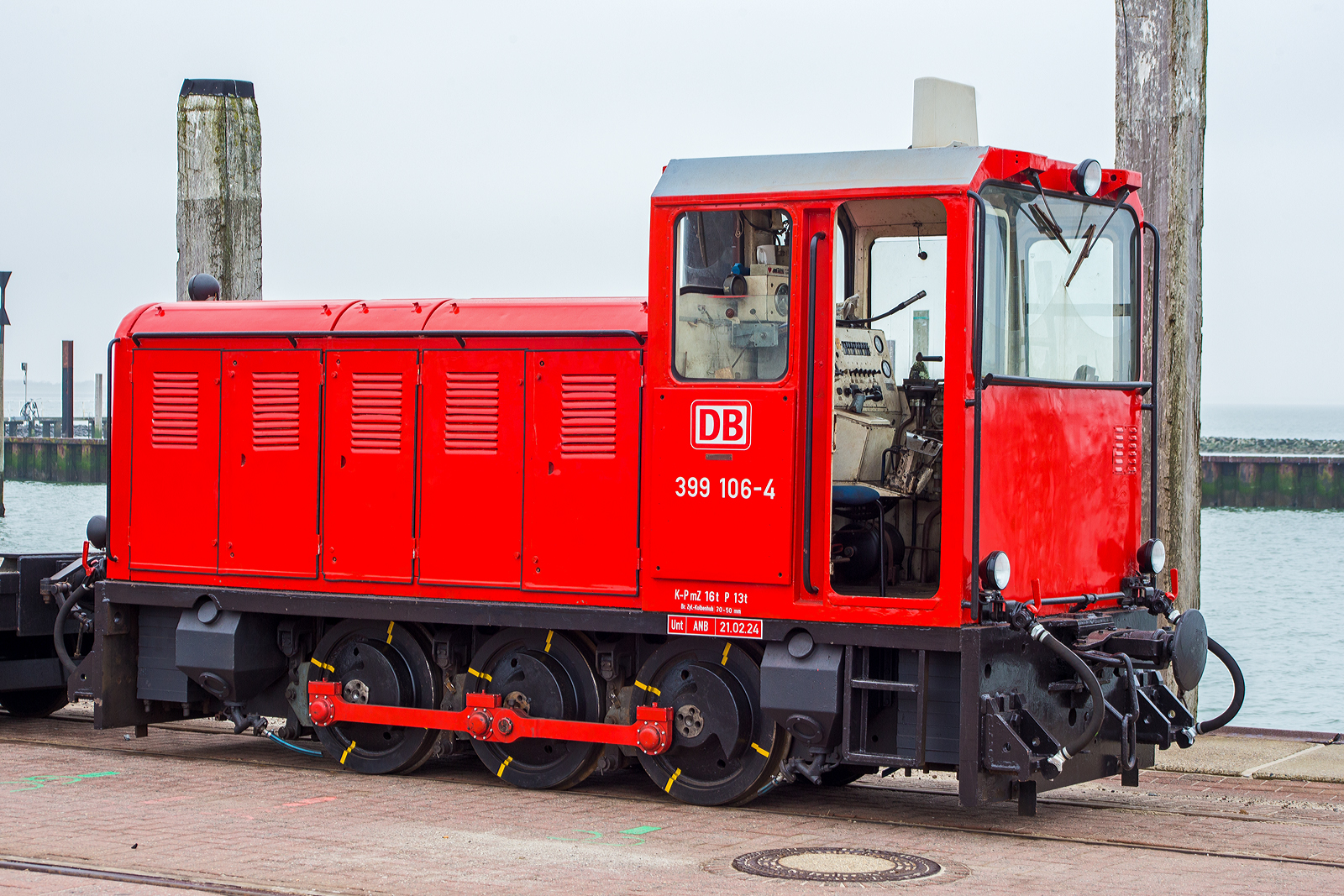 Die schmalspurige Diesellok 399 106-4 (98 80 3399 106-4 D-DB), eine der DB Fernverkehr AG bzw. der Wangerooger Inselbahn / SIW - Schifffahrt und Inselbahn Wangerooge steht am 13 März 2024, nun mit einem leeren Güterzug bestehend aus vierachsiger schmalspuriger Flachwagen DB 630xx, am Westanleger der friesischen Insel Wangerooge. Zuvor war der Güterzug beladen und wurde bereits mittels (20 t) Schwerlastgabelstapler entladen, bevor er wieder beladen wird, dies dauert aber gerade noch etwas, da gerade auch die Personenfähre MS Harlingerland angekommen ist.

Noch vor der Gründung der DB AG beschaffte die Deutsche Bundesbahn im Jahr 1992 zwei dreiachsige Kleinloks des rumänischen Typs Faur L18H vom ehemaligen Mansfeld-Kombinat für den Einsatz auf der Inselbahn Wangerooge. Sie sollten zunächst die Altbaulokomotiven der Baureihe 329 unterstützen, konnten aber die in sie gesetzten Erwartungen nicht erfüllen. Sie werden daher bis heute meist für kurze Güterzüge und als Reserve für die Personenzüge vorgehalten, wenn die Maschinen 399 107 und 399 108 nicht zur Verfügung stehen.

Die meterspurige Lok wurde 1990 vom rumänischen Hersteller FAUR S.A.(bis 1989 Faur Lokomotivwerke 23. August) in Bukarest unter der Fabriknummer 25666 gebaut und im April 1990 an das MKWP - VEB Mansfeld-Kombinat  Wilhelm Pieck  geliefert, wo sie kurz bei der zum Kombinat gehörenden meterspurige Schlackenbahn der August-Bebel-Hütte, ehemals bis 1951 Kochhütte, (eine Kupferhütte) in Helbra im Einsatz war. Am 10. September 1990 erfolgte der letzte Ofenabstich auf der Kochhütte. Die Gebäude und Betriebsanlagen wurden in den Folgejahren vollständig zurückgebaut, heute befindet sich hier ein Gewerbegebiet. So wurde bereits im November 1992 die Lok, wie eine weitere (399 105-6), an die DB - Deutsche Bundesbahn für die Wangerooger Inselbahn verkauft. Bevor sie dort zum Einsatz kam erfolgte im BW Wangerooge im Juli 1993 ein Umbau bzw. Anpassung an die EBO-Richtlinien und DB-Standards.

Insgesamt wurden zehn Diesellokomotiven der Baureihe L18H vom rumänischen Fahrzeug- und Maschinenherstellers FAUR zwischen 1983 und 1990 für verschiedene schmalspurige Wald- und Industriebahnen in Osteuropa gebaut. Es handelt sich um dreiachsige, stangengekuppelte Maschinen mit einem einseitigem Motorvorbau und Endführerstand sowie Antrieb in Z-Anordnung. Als Antrieb dient ein direkt angeflanschter Drehmomentwandler mit Lastschaltgetriebe und Achsgetriebe auf dem ersten Radsatz.

TECHNISCHE DATEN:
Spurweite: 	1.000 mm (Meterspur)
Achsformel: C
Länge über Puffer: 5250 mm
Höhe: 2.800 mm
Breite: 1.800 mm
Achsabstand: 2 x 900 = 1.800 mm
Treibraddurchmesser: 	750 mm
Kleinster befahrbarer Gleisbogen: R 20 m
Leergewicht: 16,0 t
Höchstgeschwindigkeit: 	28 km/h
Installierte Leistung: 132 kW
Motorentyp:  MAN (Lizenzbau) D2156 HM N8
Motorbauart: 6-Zylinder-Reihenmotor mit 10.350 cm³ Hubraum
Nenndrehzahl: 1.800/min
Leistungsübertragung: hydrodynamisch und mechanisch
Bremse: Druckluft
Lokbremse: Druckluft, indirekt
Kupplungstyp: Balancierhebel- bzw. Ausgleichkupplung (zp2)
