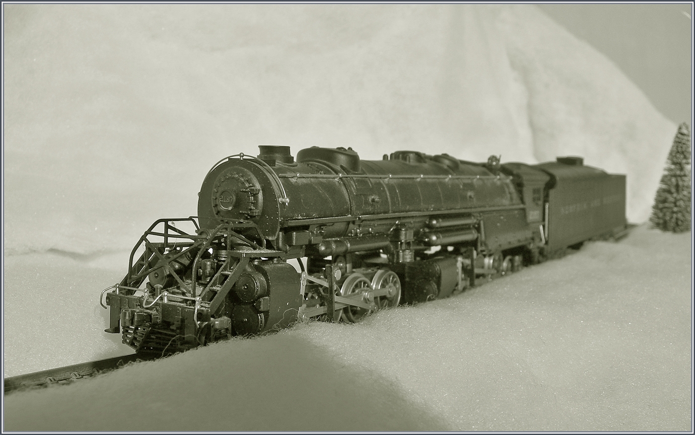 Die selbst in H0 mächtige Mallet Dampflok 2-8-8-2 - Y6b 2197 der Norfolk & Western kämpft sich durch den Schnee. Die Konstruktion der Mallet Vorbildloks Loks basiert Angaben, welche die U.S.R.A. (United States Raitroad Administration) während des Ersten Weltkriegs eingeführt hat. Die die Loks der Klasse Y6b wurde ab 1936 ausgeliefert. Grundsätzlich wurde die Klasse Y6b so konstruiert, dass sie schwere Güterzug mit 30 mp/h ziehen konnte, doch unter guten Bedingungen konnten auch bis zu 50 mp/h erreicht werden. 

Das Modell dieser Gelenklokomotive Typ Mallet „Y 6 b“ der  Norfolk & Western  dürfte gut 50 bis 60 Jahre alt sein und ist eine von der Grüsse her sehr beeindruckende Modellumsetzung. Nicht ganz logisch scheint mir, weshalb der Motor bei soviel Platz in das Führerhaus gequetscht wurde, um dann durch lange kardanischen Wellen die weit entfernten  Drehgestelle  anzutreiben. Der Tender ist vorbildgerecht mit zwei dreiachsigen  Buckeye -Drehgestellen ausgestattet, die auch zur Stromabnahme herangezogen werden. 

Das Modell dürfte gut zwanzig bis dreissig Jahre lang nicht mehr gefahren sein, nachdem ich das Modell zerlegt und bewegliche Teile entfettet und neu eingeölt habe, fährt es seit gestern wieder, auch wenn mir für den Auslauf des mächtigen Modell sowohl die Wagen als auch die Strecke fehlt. 

12. Jan. 2025