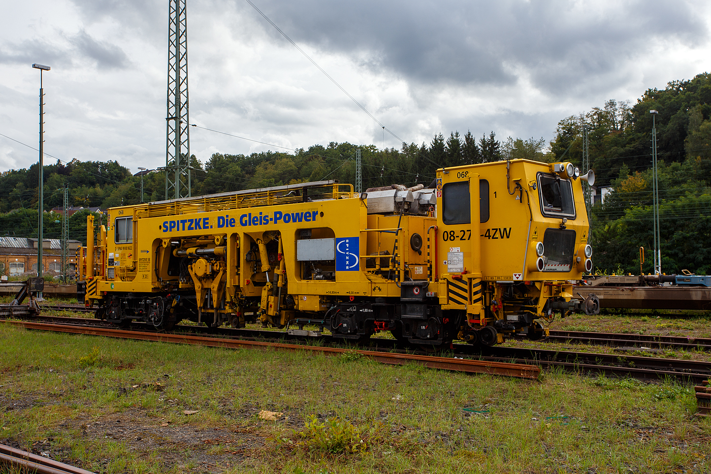Die selbstverladbare halbautomatische Nivellier-, Hebe-, Richt- und Stopfmaschinen (Zweiwege-Stopfmaschine), D-SPAG 99 80 9622 001-2 „Zicke“ (SPITZKE Maschine 068), ex 97 43 43 510 10-9, vom Typ P&T 08 - 275/4 ZW-Y, der SPITZKE SE (Großbeeren) ist am 14. September 2025 in Betzdorf/Sieg abgestellt. 

Die selbstverladbare Zweiwege-Universalstopf- und Richtmaschine 08 - 275/4 ZW-Y wurde 1996 von Plasser & Theurer, Export von Bahnbaumaschinen, Gesellschaft m.b.H. in Linz/Donau (A) unter der Maschinen-Nr. 1069 gebaut und an die Spitzke GmbH geliefert. 

Die 08-275/4 ZW-Y haben 4 Achsen (in 2 Drehgestellen), ein längsverschiebbares Stopfaggregat und ist so auch für Y-Schwellen verwendbar. Die USM 08-275 4/ZWY sind halbautomatisch arbeitende Maschinen für Nivellier-, Hebe-, Richt- und Stopfarbeiten. Sie bearbeiten Weichen und Gleise, auch Gleise mit Y-Schwellen. Ihre Leistungsfähigkeit beweisen die Zweiwege-Universalstopfmaschinen auch beim Gleisbau für Straßenbahnen, U- und S-Bahnen. Mit einer separaten Messfahrt kann die Gleisanlage nach dem Stopfvorgang automatisch protokolliert werden. 

Durch die Ausstattung mit vier Verladehubzylindern kann sich die Maschine selbstständig aus- und eingleisen, so ist sie selbstverladbar für den Straßentransport auf einen Tieflader. Somit ist ein schienenunabhängiger Transport zur und von der Baustelle möglich. Ebenso kann sich dieser Maschinentyp ohne fremde Ladehilfe aus eigener Kraft auf das Gleis setzen. Zweiwegefahrbare Maschine heißt hier nicht, dass sie eigene Räder (wie die UST 79 S) für den Straßenverkehr besitzt, sondern sie kann sich mit eigener Kraft auf einen Tieflader verladen.

Um im Havariefalle das Fahrzeug abschleppen zu können besitzt die Maschine Scharfenberg- und Rockinger-Kupplungen. Die Stopfmaschine kann zusätzlich mit anderen Drehgestellen ausgerüstet werden, um auf Straßenbahnen und auf anderen Spurweiten eingesetzt zu werden.

Die Funktionsmerkmale sind:
-	Wechsel der Arbeitsrichtung auf asphaltierten Überwegen möglich
-	Flexibler Einsatz im Bauablauf
-	Zweiwege-Maschine
-	Transport auf dem Gleis oder auf dem Tieflader
-	Laden der Maschine auf den Tieflader bzw. vom Tieflader auf das Gleis erfolgt mit eigener Maschinenhydraulik
-	Richtungslaser
-	6-Kanal-Schreiber (08-275 4/ZWY) 
-	Automatischer Leitcomputer ALC mit EM-SAT Datenverarbeitung
-	Automatische Toleranz-Überwachung für die Arbeitsqualität
-	Sifa, Indusi und Zugfunkanlage
-	Einsetzbar auf DB-, Straßenbahn- und U-Bahnstrecken (08-275 4/ZWY)

TECHNISCHE DATEN:
Spurweite: 1.435 mm (Normalspur), Umbau auf andere möglich
Achsfolge: (A'A')(A'A')
Länge über Puffer: 14.800 mm
Höhe über SO: 3.170 mm
Drehzapfenabstand: 8.000 mm
Achsabstand in den Drehgestellen: 1.800 mm
Treib- und Laufraddurchmesser: 730 mm (neu)
Eigengewicht: 36.000 kg
Achslast: 9,0 t
Motorleistung (Dieselmotor): 170 kW
Höchstgeschwindigkeit: 40 km/h (eigen und geschleppt)
Min. befahrbarer Gleisbogen: R 20 m
Zur Mitfahrt zugelassene Personen: 3

Leistungsparameter der USM 08-275 4/ZWY:
Arbeitsleistung bei Durcharbeitung im Gleis: 400 m/h
Arbeitsleistung bei Durcharbeitung im Gleis (mit Y-Schwellen): 600 m/h
Arbeitsleistung bei Durcharbeitung von Weichen: 5 Weichen in 10 h
Arbeitsradius: min. 50 m
Fahrradius: min. 20 m
Arbeiten in Überhöhung: max. 180 mm

Bemerkung: Bekanntlich kommen nach einem Stopfvorgang immer Schotterverteil- und Planiermaschine wie z.B. SSP 110 SW zum Einsatz, aber hier bei dieser ZW-Stopfmaschinen verwendet man meist, da es kleinere Bauabschnitte sind, ZW-Bagger mit entspr. Anbaugeräte (Schotterpflug und hydraulischer Schotterbesen) zum Einsatz.

Quelle: Spitzke, Plasser & Theurer und Anschriften.
Stand: September 2025
