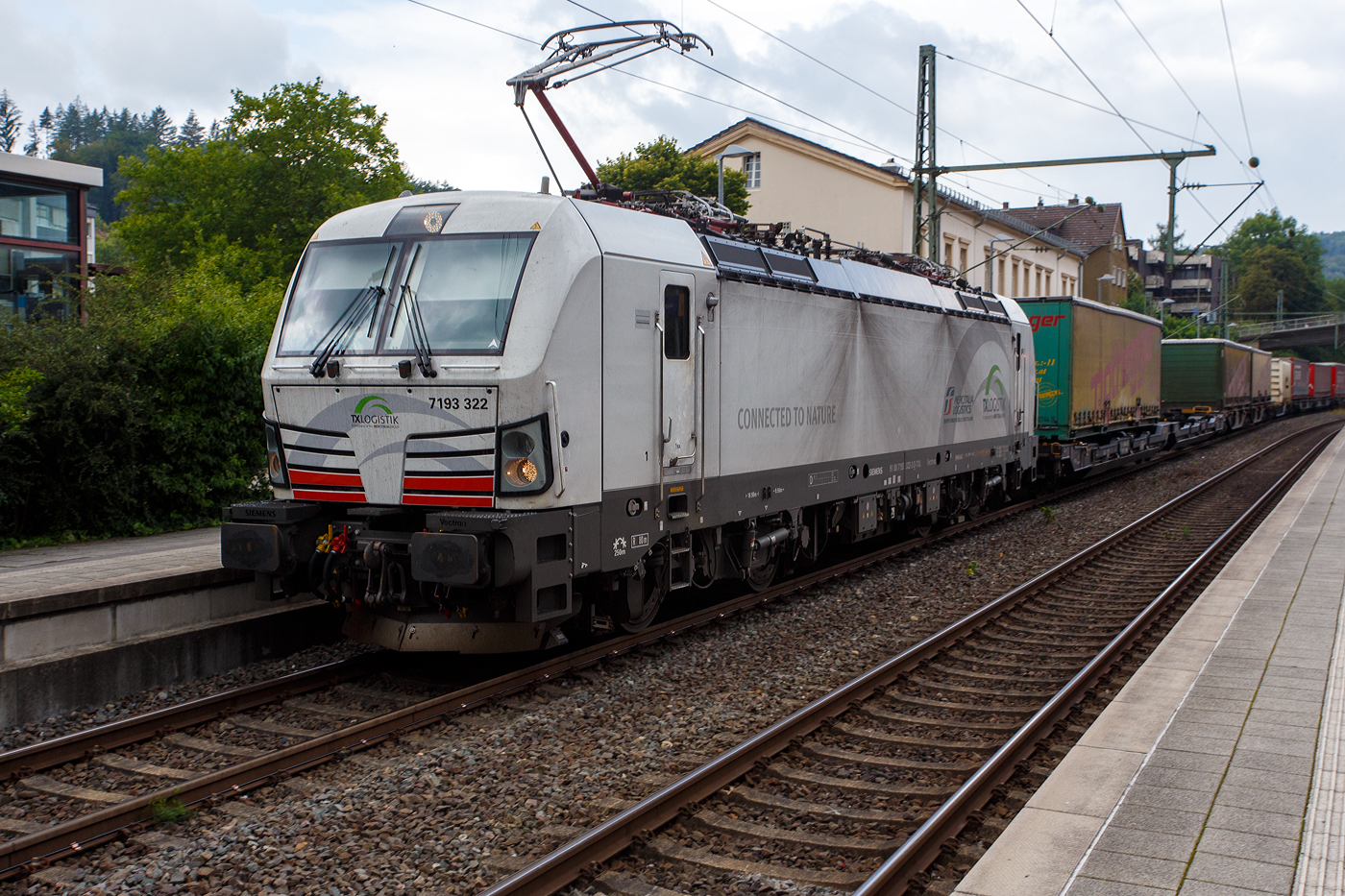 Die TXL eigene SIEMENS Vectron der TX Logistik AG, bisher hatte diese nur Loks angemietet. Die recht neue weiße TXL 7193 322 „Connected to Nature“ (91 80 7193 322-3 D-TXL) der TXL - TX Logistik AG (Troisdorf) fährt am 28 Juli 2025, mit einem KLV-Zug, durch den Bahnhof Kirchen (Sieg) in Richtung Betzdorf bzw. Köln.

Die SIEMENS Vectron MS (X4E) wurde 2024 von Siemens Mobility in München-Allach unter der Fabriknummer 23680 gebaut und am 31.03.2025 an die TXL ausgeliefert. Die mit 6.400 kW konzipierte Mehrsystemlok ist in der Variante A09-4f ausgeführt und hat so die und hat so die Zulassungen und entspr. Länderpakete für Deutschland, Österreich uns Italien (D / A / I).

Über TX Logistik AG
TX Logistik wurde 1999 als privates Eisenbahnverkehrsunternehmen gegründet und bietet mit Verbindungen in elf Ländern ein leistungsfähiges europäisches Netzwerk. Das Unternehmen verfügt über Tochtergesellschaften in der Schweiz, Österreich, Dänemark und Schweden sowie eine lokale Präsenz in Italien. In den Geschäftsbereichen Intermodal und Rail Freight entwickelt TX Logistik umfassende Schienenlösungen für kontinentale und maritime Verkehre sowie maßgeschneiderte Konzepte für konventionelle Fracht. Mit 650 Mitarbeitern und 8,6 Milliarden gefahrenen Tonnenkilometern erwirtschaftete das Unternehmen 2021 einen Jahresumsatz von 253 Millionen Euro. Seit Januar 2017 gehört TX Logistik zu 100 Prozent der Mercitalia Logistics S.p.A., einer Tochtergesellschaft der FS - Ferrovie dello Stato Italiane. Mittlerweile gehört das Unternehmen mit zu den Größten für den Schienengüterverkehr in Europa.

Das Unternehmen bietet den ganzen Umfang an Schienengüterverkehr, inklusive Containertransport und kombiniertem Verkehr an. Wichtigste Transportstrecken sind von den Häfen Hamburg, Bremerhaven, Rotterdam und Antwerpen nach Süddeutschland, Schweiz, Österreich und Italien.

TX Logistik setzt nun auf eigene Vectron Loks:
Anfang Oktober 2024 hat die TX Logistik AG ersten drei von 40 modernen Vectron-Lokomotiven des Herstellers Siemens Mobility aufs Gleis gesetzt, die das zur Mercitalia Logistics (FS Italiane Group) gehörende Schienenlogistikunternehmen im Mai 2023 bestellt hatte. Die Erweiterung der Fahrzeugflotte ist für TX Logistik eine wichtige Voraussetzung, um im intermodalen und grenzüberschreitenden Schienengüterverkehr weiter zu wachsen. Die neuen Lokomotiven werden vor allem auf dem Brenner- und dem Schweiz-Korridor eingesetzt, den strategisch wichtigen Nord-Süd-Achsen in Europa.

Beide Korridore sind stark frequentiert und stellen hohe Anforderungen an die eingesetzten Lokomotiven – von der Zugkraft über die Stabilität bis hin zur grenzüberschreitenden Systemkompatibilität. TX Logistik hat dazu die Maschinen mit verschiedenen Länderpaketen bestellt. 20 Vectron erhalten das Länderpaket für den Betrieb in Deutschland, Österreich, Schweiz, Italien und den Niederlanden (D-A-CH-I-NL) und sollen bis Anfang 2025 übergeben werden. Die Auslieferung der 20 Lokomotiven mit der Ausstattung für den deutsch-österreichisch-italienischen Korridor (D-A-I) soll bis zum Jahresende 2025 erfolgen.

Die Entscheidung für den Kauf der Vectron-Lokomotiven unterstreicht zugleich das Bestreben von TXLogistik, Schienengüterverkehre als umweltfreundliche und effiziente Alternative zum Straßentransport weiter voranzutreiben. Um dies zu unterstreichen und gleichzeitig für den Einstieg in den intermodalen Transport zu werben, hat die erste der drei Vectrons, die im Zughotel in Braunschweig übergeben wurden, eine spezielle Lok-Beklebung mit dem Schriftzug „Start now (Nature). Driven by Green Passion“ erhalten.

Die neuen Loks bieten mit ihrer Flexibilität und Leistungsfähigkeit ideale technische Voraussetzungen, um den steigenden Anforderungen des europäischen Güterverkehrs gerecht zu werden. Mit der modernen Vectron-Flotte, so TX Logistik, sei man mittelfristig nun in der Lage, die Kapazitäten auf dem Brenner- und dem Schweiz-Korridor deutlich zu erhöhen sowie die Effizienz und Zuverlässigkeit im Schienengüterverkehr weiter zu verbessern.