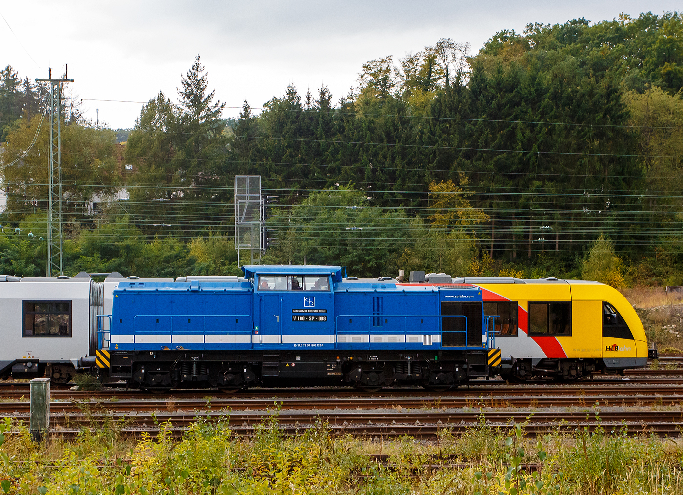 Die V 100-SP-008 / 203 128-4 (92 80 1203 128-4 D-SLG) der SLG Spitzke Logistik GmbH, ex DR 110 529-5, ex DR 112 529-3, ex DR 202 529-4, ex DB 202 529-4, rangiert am 30 September 2025 im Rbf Betzdorf/Sieg.

Die V 100.1 wurde 1973 von LEW (VEB Lokomotivbau Elektrotechnische Werke „Hans Beimler“ Hennigsdorf) unter der Fabriknummer 13568 gebaut und an die DR als 110 529-5 ausgeliefert. Der Umbau in DR 112 529-3 erfolgte 1985, eine Umzeichnung in 202 529-4 erfolgte 1992 und 1994 ging sie dann mit in die DB über. Die z-Stellung und Ausmusterung erfolgten 1997/1998. Dann ging sie zur SFZ - Schienenfahrzeugzentrum Stendal, ab 01.11.2002 ALS - ALSTOM Lokomotiven Service GmbH, dort wurde sie auch 
gemäß Umbaukonzept BR 203.1 umgebaut. Seit dem 20.07.2007 fährt sie nun für die SLG - Spitzke Logistik GmbH in Großbeeren als V 100-SP-008 (80 1203 128-4 D-SLG).

TECHNISCHE DATEN:
Spurweite: 1.435 mm (Normalspur)
Achsanordnung: B'B' 
Länge über Puffer: 14.240 mm
Radsatzabstand im Drehgestell: 2.300 mm
Drehzapfenabstand: 7.000 mm
Kleinster befahrbarer Gleisbogenradius: 100 m
Dienstgewicht: 68 t
Leistungsübertragung: dieselhydraulisch
Höchstgeschwindigkeit: 100 km/h
Kleinste Dauerfahrgeschwindigkeit: 11,1 km/h

Motortyp: Caterpillar 3512 B DI-TA
Motorbauart: 12-Zylinder-Dieselmotor mit Direkteinspritzung, Abgasturbolader und Ladeluftkühlung
Motorleitung: 1.305 kW (1.775 PS) bei 1.600 U/min
Hubraum: 51,8 l (Bohrung-Ø 170 x Hub 190 mm)
Motorgewicht: 6.537 kg
Getriebe: Voith Strömungsgetriebe GSR 30/5,7
Betriebsstoffvorräte: 2.500 l (Dieselkraftstoff)
Bremse: Klotzbremse, KE-GP m. Z