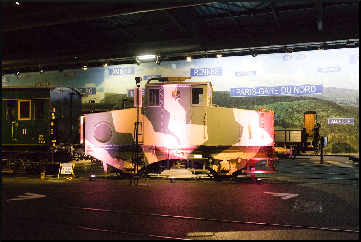 Diese kleine zweiachsige Lok in Tarnfarben, hergestellt von s'Chamond, stand kräftig angestrahlt auf einem der Mittelgleise im Eisenbahnmuseum Cite du Train Mulhouse. Baujahr und Einsatz sind leider unbekannt, vielleicht hat jemand Infos? Fotografiert wurde sie bei einem Besuch am 10.11.2023.