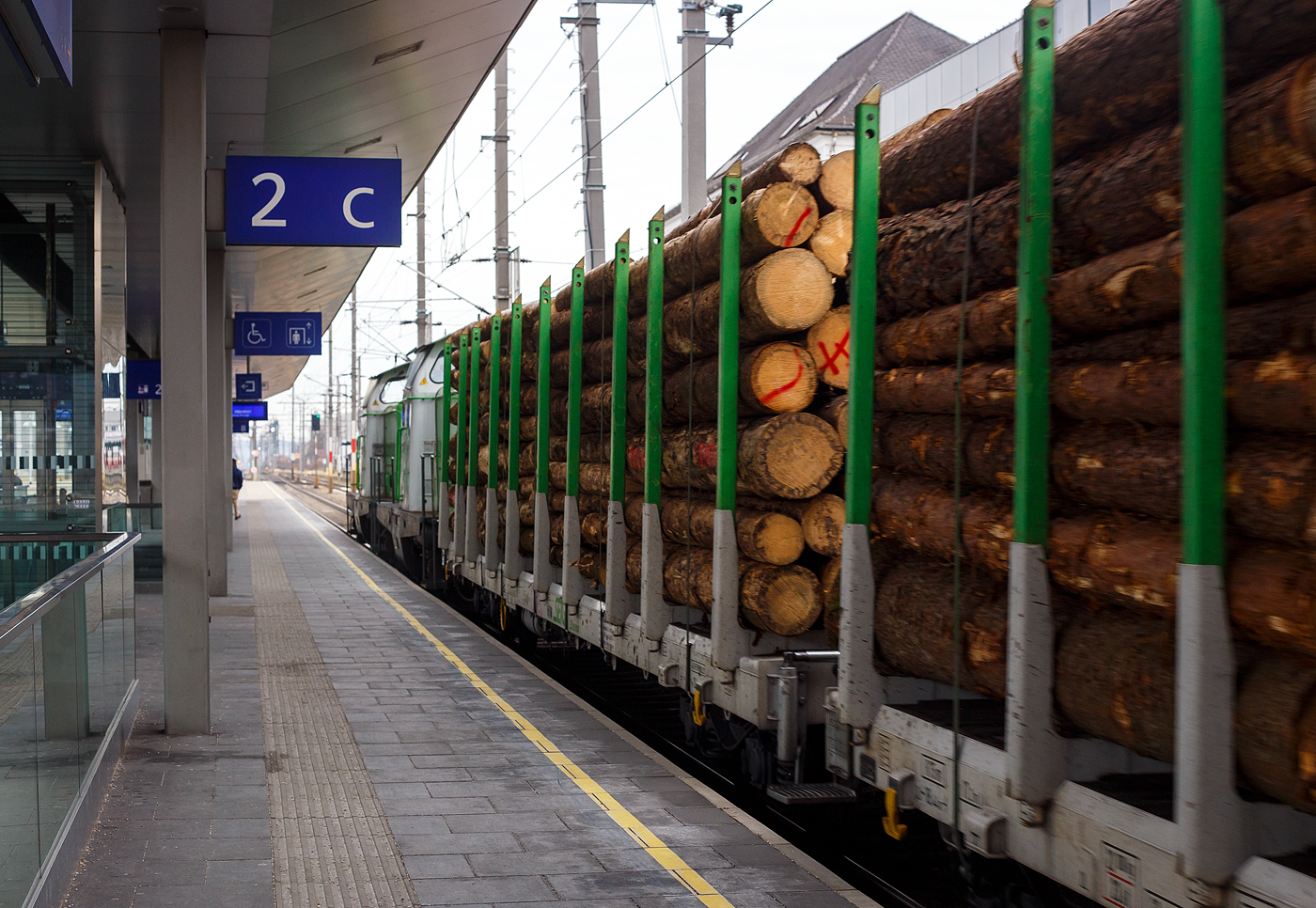 Direkt hinter den beiden V 100 (ex DB BR 211), V100.54 und V100.53 der SETG - Salzburger Eisenbahn Transportlogistik GmbH (auch S-Rail GmbH oder S-Fleet GmbH) am 14 Januar 2025 bei der Zugdurchfahrt im Bahnhof Attnang-Puchheim, ein mit Fichtenrundholz beladener vierachsiger Drehgestell-Flachwagen mit Rungen (Rungenwagen) D-SRA 4723 xxx-x der Gattung Snps „SFlexwood“ der SETG.

Die Salzburger EisenbahnTransportLogistik GmbH (SETG) investierte als erste Privatbahn Europa‘s in Neubau-Rungenwaggons. Das österreichische Eisenbahnunternehmen SETG hat gemeinsam mit dem slowakischen Hersteller Tatravagónka a.s. (in Poprad) einen neuen Holztransportwaggon namens Snps „SFlexwood“ entwickelt. Gegenüber herkömmlichen Rungenwagen verfügt die Neukonstruktion mit 8,8 m² über einen deutlich größeren Ladequerschnitt. Die Waggons sind mit Rungen ausgestattet, die sowohl Rundholz- als auch Schnittholztransport ermöglichen. Teile des Rungenschemels sind dazu im Wagenboden integriert, damit beim Schnittholztransport die gesamten Breite zur Verfügung steht. Die Sortimentslängen können 2,5 bis 17 m betragen und die Nutzlast liegt bei 68 t. Durch den Verzicht auf Stirnwände sollen sich bis zu 25% Fahrenergie einsparen lassen. Insgesamt hat die SETG 180 Einheiten des SFlexwood erhalten, remisiert bzw. einstellt sind sie in Deutschland als D-SRA 4723 xxx-x, die internationale Verwendungsfähigkeit ist TEN-CW. 

SFLEXWOOD ist der neue Standard-Holzwaggon: für unterschiedliche Holzlängen, Rund- und Schnittholz, kundenspezifische Zugslängen und maximal ökologisch.

Kenndaten:
Bei 17,20 m Ladelänge und Bauprofil ‚G2‘ waren letztendlich 8,8 m² Ladequerschnitt das Ergebnis detaillierter Planung. Dies stellt den größten Ladequerschnitt aller Rundholzwaggons in Europa dar. Über 68 Tonnen Nutzlast pro Waggon ergeben ein Ladungsgewicht pro Zug von max. 2.380 Tonnen. Je nach Holzbeschaffenheit lassen sich auf einem SFLEXWOOD-Zug somit bis zu 2.500 Festmeter (fm) verladen. Oder bis zu 4.200 Kubikmeter (m³) Schnittholz pro Zug. Soviel wie noch nie auf Zügen in Zentral- und Osteuropa auf Ganzzügen für den Holztransport Platz gefunden hat. Der SFLEXWOOD ist universell in den meisten Ländern Europas einsetzbar – eine wichtige Voraussetzung im flexiblen Holz-Transportmarkt. Die kompakte Länge des SFLEXWOOD-Waggons ermöglicht flexible, kundenspezifische Zuglängen, weniger Rangierbewegungen bei Be- und Entladung und damit eine optimale Auslastung der oft kurzen Lade-/Entladegleise.

Die Wagenkonstruktion ist für eine Achslast von 25 t aus der Sicht der Festigkeit ausgelegt. Der Wagen ist mit einem 70 mm dicken Holzboden und einer Ladekante ausgestattet, die den Wagenfußboden vor Beschädigungen schützt. Der Fußboden erfordert nur geringen Aufwand. Alle Bedienelemente befinden sich unter dem seitlichen Längsträger und sind so vor ungewollten Beschädigungen während der Handhabung mit dem Ladegut geschützt.

Bahngeschichte geschrieben:
Zum ersten Mal seit dem zweiten Weltkrieg hat in Europa eine Privatbahn in den Neubau von Waggons für den Holztransport investiert. Die SETG stärkt damit in ihrem Kernsegment, dem Transport von Forstprodukten, ihre Kompetenz und bietet ihren Kunden ab sofort den maximal größten und maximal flexibelsten Holz-Ganzzug an: SFLEXWOOD.

TECHNISCHE DATEN der SFLEXWOOD-Wagen:
Hersteller: Tatravagónka a.s., in Poprad (Slowakei)
Baujahr: ab 2023
Spurweite: 1.435 mm (Normalspur)
Länge über Puffer: 18.440 mm
Drehzapfenabstand: 12.900 mm
Achsabstand im Drehgestell: 1.800 mm
Laufraddurchmesser: 920 mm (neu) 
Drehgestelltyp: Y25 Ls-K
Ladefläche: 46,8 m²
Ladelänge: 17.200 mm
Höhe der Ladeebene über SOK: 1.260 mm
Anzahl der Rungenpaare: 10
Rungenhöhe: 2.410 mm
Eigengewicht: ca. 22,0 t
Max. Zuladung bei Lastgrenze S: ca. 68,0 t (ab Streckenklasse D)
Max. Geschwindigkeit: 100 km/h (beladen) / 120 km/h (leer)
Max. Radsatzlast: 22,5 t
Intern. Verwendungsfähigkeit: TEN / CW