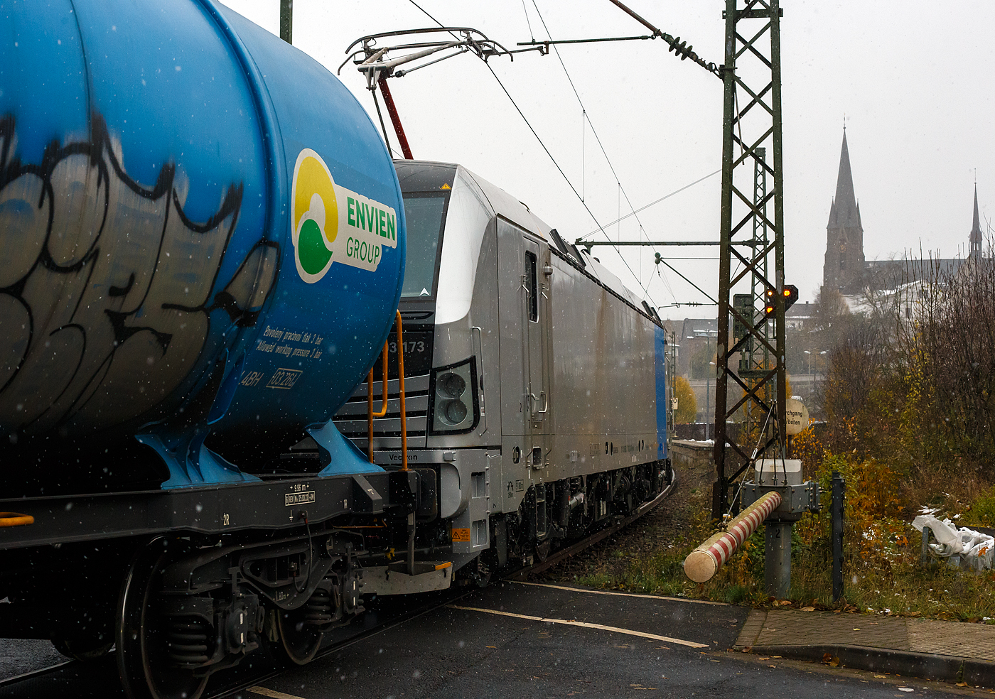 Eigentlich war ich auf die Ausfahrt von dem RE 9 am 22 November 2024 bei Schneefall aus Bahnhof Kirchen/Sieg fokussiert auch die Sicht in die Gegenrichtung war durchs Schalthaus vom Bü verdeckt, so schlich sich die fast fabrikneue SIEMENS Vectron MS 6193 173 (91 80 6193 173-2 D-Rpool) der Railpool mit einem Kesselwagenzug in Richtung Siegen heran. Daher war hier nur noch der Nachschuss möglich. Daher kann ich manchmal die Diskussionen über Bahnlärm nicht verstehe, den Güterzug konnte ich nur auf den letzten Metern hören. 

Die SIEMENS Vectron MS wurde 2024 von SIEMENS Mobilitiy in München-Allach unter der Fabriknummer 23499 gebaut.