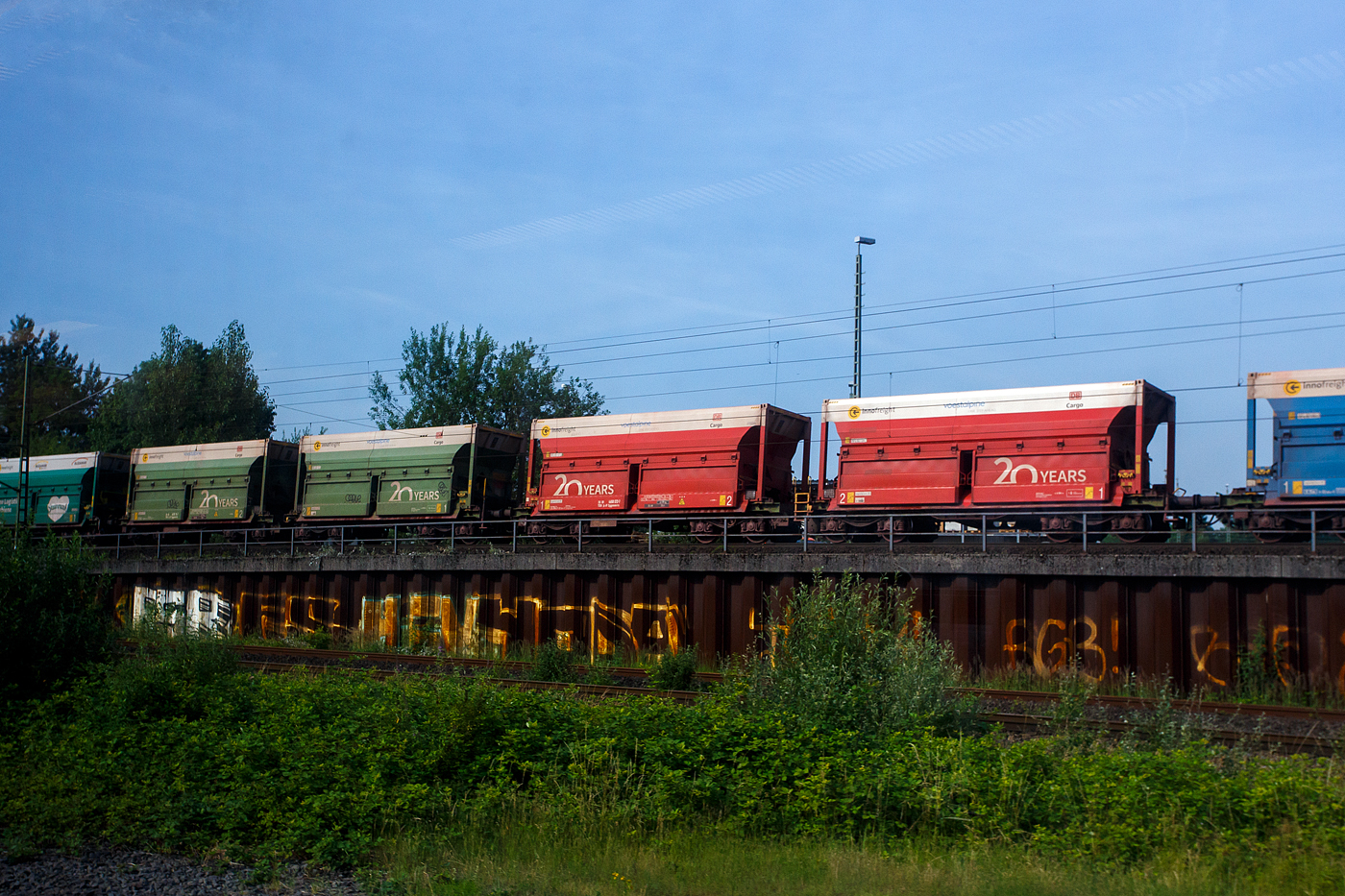 Ein etwas anderer Erzwagen - RockTainer ORE - Variante D, ein 2 x 4-achsiger Flachwagen in Sonderbauart (Doppelwagen) bzw. ein 8-achsiger Containertragwagen, 35 81 4658 072-7 A-IF, der Gattung Sggmmrrs 60ft, der �sterreichischen INNOFREIGHT mit zwei aufgesetzten 30 ft RockTainer ORE (Variante C01), am 18 Juni 2025 im Zugverband bei K�ln-Gremberg, aus einem Zug fotografiert. 

Grunds�tzlich besteht ein InnoWaggon aus zwei kurzgekuppelten Einzelwagen. Leichtbauweise und hohe Belastbarkeit differenzieren diese Waggons dabei klar von anderen und erm�glichen deutlich h�here Zuladung f�r den Transport von unterschiedlichsten G�tern. Der InnoWaggon vereint den Tragwagen und die auswechselbaren Beh�lter zu einem innovativen Konzept, das eine flexible Nutzung verspricht. Der Einsatz der Spezialbeh�lter wird dabei der jeweiligen Branche angepasst, da die Beh�lter je nach Anforderung wie spezifisches Sch�ttgewicht oder Entladestation eingesetzt werden.

Als Teil der INNOFREIGHT RockTainer Systeme wurde der RockTainer ORE f�r den Transport von Eisenerz, Erzpellets und Kalkstein optimiert. Mit einem Ladevolumen von 47 m� k�nnen bis zu 138 Tonnen an Material in nur einem RockTainer ORE transportiert werden. Die Entladung erfolgt schlagartig in einen Tiefbunker. Ein Ganzzug besteht meist aus 27 Wagen und transportiert so rund 3.700 Tonnen Erz.

TECHNISCHE DATEN eines 60 ft InnoWaggon:
Gattung: Sggrrs
Gattungskennzahl: 4658
Hersteller (Wagen): Tatravag�nka a.s. Poprad (Slowakei)
Baujahr: 2018
Spurweite: 1.435 mm (Normalspur)
Achsenanzahl: 8 pro Doppelwagen (in 4 Drehgestellen)
L�nge �ber Puffer: 22.500 mm 
Breite: 2.890 mm
Drehzapfenabstand: 2 x 6.010 mm
Achsabstand in den Drehgestellen: 1.800 mm
Raddurchmesser: 920 mm (neu)
L�nge Ladefl�che: 2 x 9.125 mm (2 x 30 ft)
H�he der Ladefl�che �ber SOK: 1.155 mm
Eigengewicht: ca. 40.600 kg
Max. Geschwindigkeit: 100 km/h (beladen) / 120 km/h (leer)
Max. Zuladung pro Doppelwagen: 138,5 t (ab Streckenklasse D4)
Max. Achslast 22,5 t
Bremse: KE-GP-A (K)
Bremssohle: Jurid 822
Kleinster befahrbarer Gleisbogen: R = 75m
Intern. Verwendungsf�higkeit: TEN-GE

TECHNISCH DATEN eines RockTainer ORE:
L�nge: 30 ft / 9.125 mm
H�he: 2.900 mm ab OK Wagen (3.233 mit Rutschen)
Breite: 3.050 mm
Eigenwicht: ca. 6.300 kg
Ladevolumen: 47 m�
