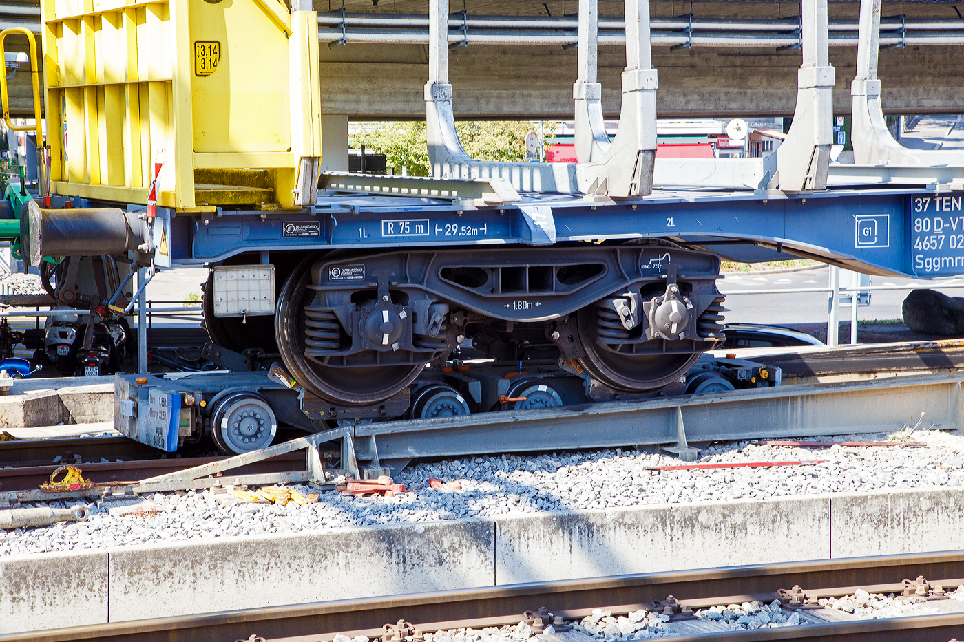 Ein normalspuriges Drehgestell des leeren 2 x vierachsiger Flachwagen in Sonderbauart (INNOFREIGHT Holz-Doppelwagen), 37 80 4657 028-9 D-VTG, der Gattung Sggmrrs S240, verladen auf zwei schmalspurige Rollböcke Ua 2xx vom Typ Vevey, am 07 September 2023 an einer Rollbockgrube beim Bahnhof Morges.

Die Rollböcke dienen zum Transport von Normalspurwagen (meist Güterwagen) auf Schmalspurgleisen (wie hier 1.000 mm). Ein Rollbock ist 1,65 t schwer und trägt jeweils eine Normalspur-Wagonachse mit einer maximalen Achslast von 22,5 t. Bei z.B. einem vierachsigen Drehgestell Wagen kommen so vier Rollböcke zum Einsatz, wobei der Wagen somit bis zu 90 t schwer sein kann.

TECHNISCHE DATEN:
Spurweite: 1.000 mm
Achsanzahl: 2
Eigengewicht: 1,65 t
Traglast: 22,5 t 

Ein Rollbock ist ein meist zweiachsiges Schienenfahrzeug (Wagen), mit dem ein andersspuriges Eisenbahnfahrzeug auf der Spurweite des Rollbocks befördert werden kann. In Süddeutschland wird er auch als Rollschemel bezeichnet, nicht aber in der Schweiz, wo dieses Wort einen Rollwagen bezeichnet. Entwickelt wurde der Rollbock 1881 von Paul Langbein (1842–1908).

Funktion:
Durch den Einsatz von Rollböcken entfällt im Güterverkehr das Umladen der Güter in Fahrzeuge der anderen Spurweite. Das Aufbocken von Personenwagen war nicht üblich, da die Reisenden selbst relativ leicht die Fahrzeuge wechseln konnten und das Kipp-Risiko bei Personenbeförderung nicht akzeptabel war. Zu besonderen Anlässen wurden aber Spezialwagen verladen, beispielsweise Salon- oder Kinowagen. Grundsätzlich ist anzumerken, dass es, insbesondere in Deutschland, kein zusammenhängendes Schmalspurnetz, ähnlich jenem in Normalspur, gibt oder gab. Daher war eine weitgehende Normung und Standardisierung, die bei den normalspurigen Eisenbahnen die Interoperabilität sicherstellt, nicht zwingend und fand nicht statt. Folglich kam es zu zahlreichen technischen Insellösungen, auch bei den Rollböcken. Die grundsätzliche Funktion ist aber stets dieselbe. Neben technischen Unterschieden waren daraus folgend die Vorschriften für den Betrieb verschieden, wobei die Vorschriften zum Teil die Technik beeinflussten, zum Teil aber auch in der Folge der technischen Voraussetzungen erlassen wurden.

Rollböcke werden seitens der Eisenbahnindustrie im Übrigen auch dafür eingesetzt, andersspurige Fahrzeuge über Normalspur vom Hersteller zu Testeinrichtungen oder zu ihrem Einsatzgebiet zu transportieren. So setzt die RailAdventure GmbH solche Fahrzeuge – bei ihr Loco Buggys genannt – ein.

Technik
Der Rollbock ist ein schmalspuriges Fahrzeug mit sehr kurzem Achsstand (ähnlich einem Drehgestell), auf dem die Räder jeweils eines Radsatzes des Normalspurwagens verankert werden. Beladen wird der Rollbock von einer speziellen Rollbockgrube aus. Abhängig von der konkreten Ausgestaltung der Rollböcke konnten auch dreiachsige Wagen aufgebockt werden. 

Güterwagen auf Rollböcken (oder Rollwagen) können zu ganzen Güterzügen zusammengestellt werden. Je nach örtlicher Betriebsvorschrift konnten schmalspurige Personenwagen in die Züge eingereiht werden, häufig waren die Reihungsfolgen reglementiert. Zum Teil waren bzw. sind die Rollböcke mit dem jeweiligen Bremssystem (Druckluft, Saugluft) oder Heberleinbremse der Schmalspurbahn ausgerüstet, es gab aber auch ungebremste Rollböcke. Einige Bahnen stellten in diesem Fall so genannte Bremswagen in die Züge ein, die ballastiert waren, um größeres Bremsvermögen zu besitzen. Teilweise wurden die Bremsleitungen der Normalspurwagen mitverwendet und die Rollbockbremsen über T-Stücke an diese angeschlossen. Normalspurwagen auf Rollböcken werden entweder direkt miteinander gekuppelt oder die Rollböcke mittels Kuppelstangen verbunden. Bei der direkten Kupplung sind diese „lang zu machen“, das heißt, nicht straff anzuziehen, da die Puffer die Wagen in den häufig engen Radien sonst von den Rollböcken drücken würden. Die Verbindung mit dem Zugfahrzeug kann ebenfalls über Kuppelstangen erfolgen. Es gibt aber auch die Möglichkeit, so genannte Pufferwagen zu verwenden. Diese schmalspurigen Wagen besitzen Zug- und Stoßvorrichtungen, die in Ausführung und Höhe zu jenen der aufgebockten Normalspurwagen passen und somit als Adapter dienen. Es wurden auch Lokomotiven mit solchen angepassten Normalspur-Zug-und-Stoßvorrichtungen verwendet.

Rollböcke nach dem System Vevey
Um den beim System Langbein personal- und zeitaufwändigen Verladevorgang zu vereinfachen, entwickelte die schweizerische Bahngesellschaft YSteC 1974 ein neues Prinzip. Hierbei wird die Achse des Normalspurwagens nicht mehr fixiert. Der Wagen steht mit seinen Rädern in speziell geformten Mulden. Derartige Rollböcke, als System „Vevey“ von den Ateliers de constructions mécaniques de Vevey (ACMV) in Serie gefertigt, werden bei mehreren Bahnen in der Schweiz und einer Bahn in Deutschland (HSB) eingesetzt. Der Hauptunterschied zum klassischen Rollbock ist, dass das Aufbocken bei langsamer Fahrt automatisch geschieht. Somit sind zahlreiche Unannehmlichkeiten und Gefährdungspotenziale behoben, weswegen beispielsweise die Harzer Schmalspurbahnen ihre Rollwagen durch solcherlei Rollböcke ersetzt haben, ähnlich wie zuvor diverse Schweizer Bahnen.

Die mögliche Rationalisierung konnte aber nicht verhindern, dass der Güterverkehr auf zahlreichen Schmalspurbahnen dennoch eingestellt wurde. Rollbockanlagen im kommerziellen Betrieb gibt es nur noch in Nordhausen, Langenthal, Morges und Yverdon, die Anlage in Worblaufen dient noch Diensttransporten. In Interlaken Ost wurde 2021 eine neue Rollbockanlage erstellt.