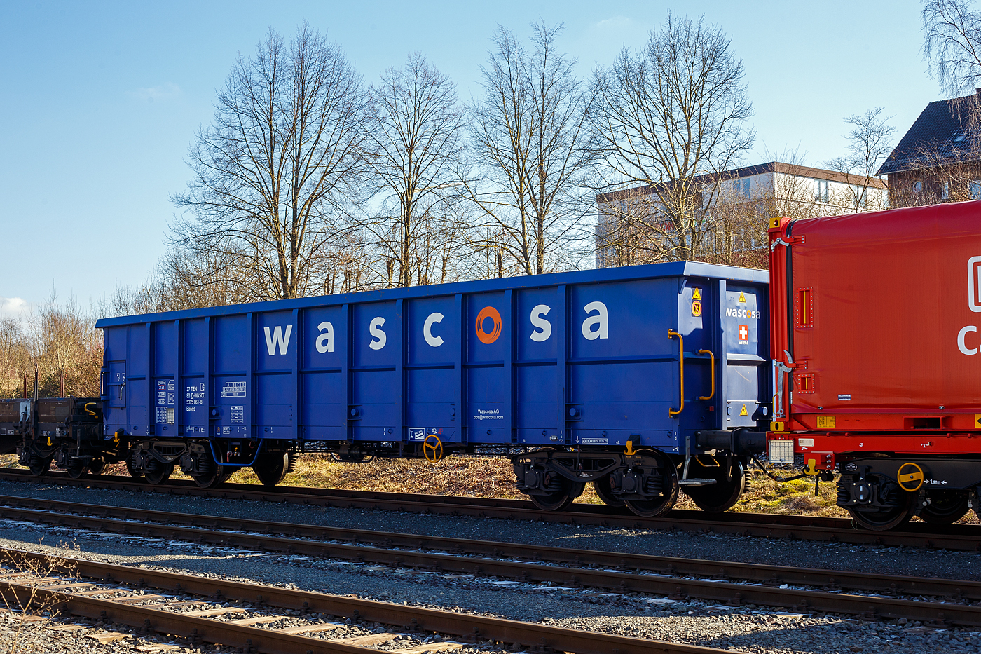 Ein recht neuer vierachsiger offener 82,5m³ Drehgestell-Güterwagen (Hochbordwagen) der Gattung Eanos, 37 80 5375 061-8 D-WASCO, der Wascosa AG, Luzern (CH), am 17 Februar 2025 abgestellt, im Zugverband eines Übergabegüterzuges, in Herdorf auf dem KSW Rbf Herdorf (Betriebsstätte Freien Grunder Eisenbahn - NE 447).

Der Wagen wurde 2023 von Astra Rail Industries (ARI) in Arad (Rumänien), seit 2016 Werk der Greenbrier Europe, gebaut.

Der Wagen ist für den Transport von Eisenschrott, Kohle sowie diversen Schüttgütern. Es ist ein robuster Wagen, da die Wände und der Boden in verstärkter Stahlkonstruktion, aus unlegiertem Baustahl S355J2+N, gefertigt sind. Die Blechdicken betragen 4 mm bei Seitenwand, 6 mm bei Stirnwand und 8 mm beim Boden. Die Wagen haben eine verstärkte Zugeinrichtung und ist für automatische Kupplungen (DAK) vorbereitet. 

Auffällig bei diesen Wagen ist, das sie keine große 2-flügelige Tür besitzen, sondern nur eine kleine Tür 750 x 930 mm je Wagenseite besitzen (hier links im Bild). 

TECHNISCHE DATEN:
Spurweite: 1.435 mm (Normalspur)
Achsanzahl: 4 in zwei Drehgestellen
Länge über Puffer: 15.740 mm
Drehzapfenabstand: 10.700 mm
Achsabstand im Drehgestell: 1.800 mm
Laufraddurchmesser: 920 mm (neu)
Drehgestelle: Y25 Lsd-KP1 (V)
Puffer: Gruppe A, Hub 105 mm
Länge x Breite der Beladeöffnung: 14.492 x 2.720 mm
Ladelänge: 14.490 mm
Ladefläche: 39,4 m²
Laderaum:  82,5 m³
Höchstgeschwindigkeit: 100 km/h (beladen) / 120 km/h (leer)
Max. Ladegewicht: 59,0 t ab Streckenklasse C, 67,0 t ab Streckenklasse D
Eigengewicht: 23.000 kg
Kleinster bef. Gleisbogenradius: R 35 m (im Wagenverbund150 m)
Bremse: KE-GR-A (K)
Bremssohle: Jurid C 810
Handbremse: Ja
Intern. Verwendungsfähigkeit: TEN-GE
