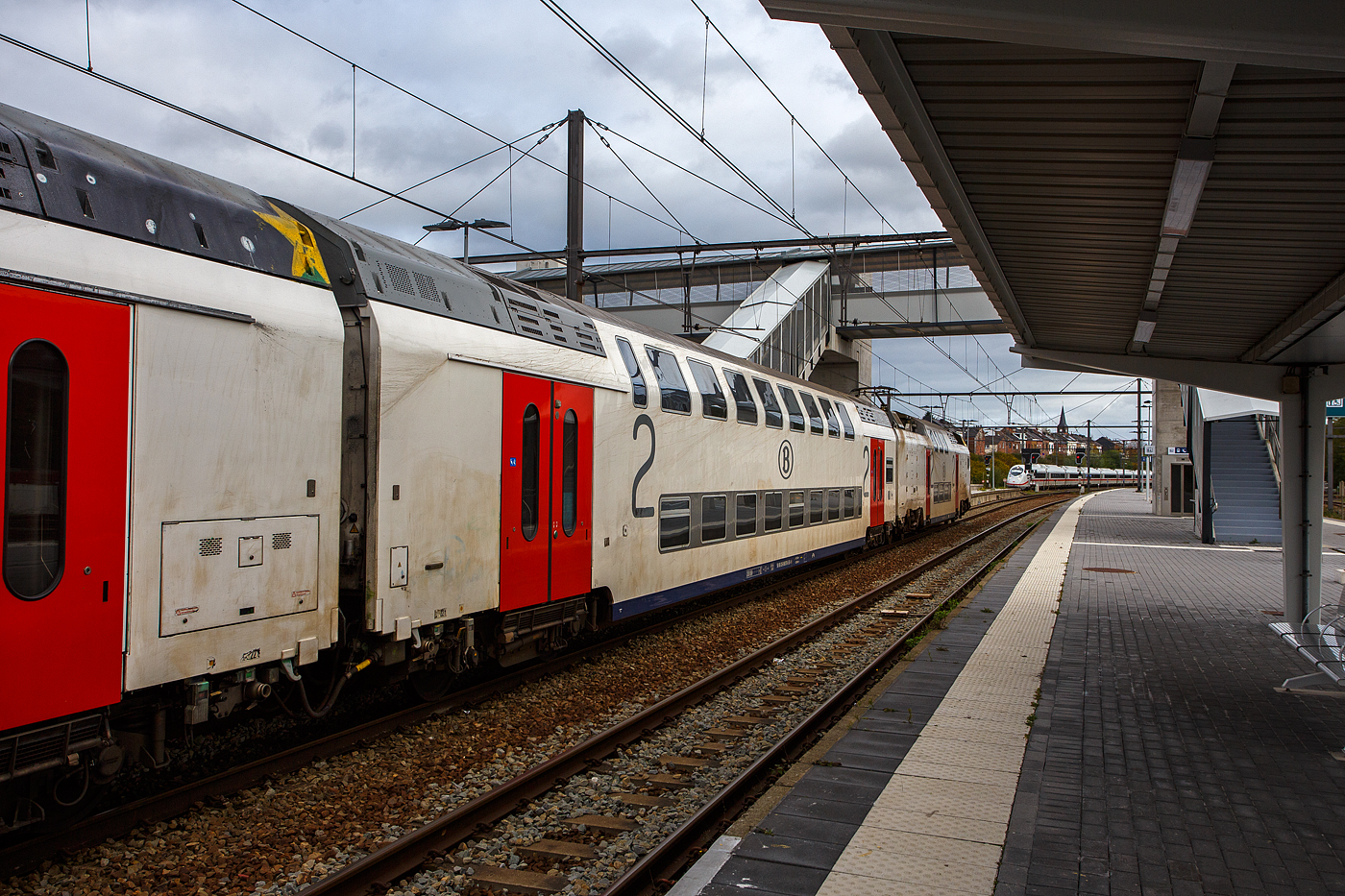Gef�hrt von dem SNCB/NMBS - M7 Bmx TWINDEXX-Triebwagen 91 88 8696 10 7-0 B-B, ex 76107, f�hrt der IC 2811 von Knokke �ber Gent und Br�ssel nach L�ttich/Li�ge-Guillemins, am 21 Oktober 2025 vom Bahnhof Ans seinem baldigen Ziel entgegen. W�hrend hinten auf der Hochgeschwindigkeitsstrecke LGV 2 (L�ttich und Br�ssel-Midi) ein ICE 3 neo / Siemens Velaro MS der DB-Baureihe 408 in Richtung Br�ssel durchrauscht. 