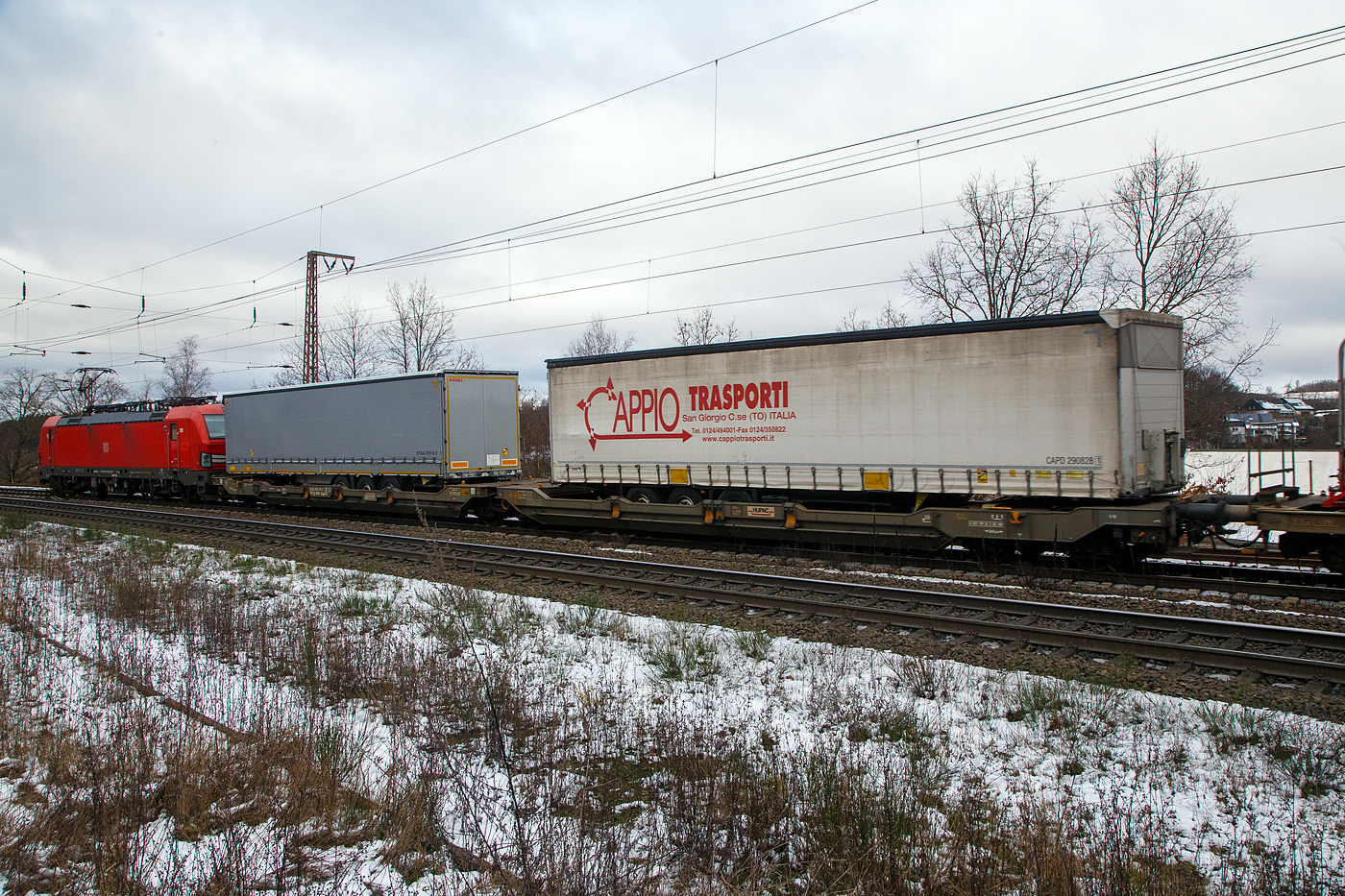 Hinter der DB 193 323-3....Der sechsachsige Gelenk-Taschenwagen (Doppeltaschenwagen in Gelenkbauart), 33 85 4956 771-7 CH-HUPAC der Gattung Sdggmrss, der HUPAC Intermodal SA, am 27.01.2023 im Zugverband bei der Durchfahrt in Rudersdorf (Kr. Siegen), im Zugverband bei der Durchfahrt in Rudersdorf (Kr. Siegen), hier beladen mit zwei Sattelanhngern.

Diese Wagen vom Typ T5/T3000e wurde von Tatravagnka a.s. in Poprad (Slowakei) ab 2015 gebaut, die Entwicklung und auch Lizenzgeber ist die Ferriere Cattaneo SA in Giubiasco (Schweiz). Baugleiche Wagen sind auch bei anderen Halteren im Einsatz, die jeweils die Gattungskennzahl 4956 haben. Mgliche Ladeeinheiten sind zwei kranmanipulierbare Sattelauflieger oder alternativ bis zu vier Wechselbrcken und/oder Container. Dafr besitzt der Wagen einen dreifach verstellbaren Sttzbock sowie fr die Ladungseinheiten feste und klappbare Aufsetzzapfen auf den Langtrgern. Das maximale Zuladegewicht betrgt fr Sattelauflieger 2  40 t; die Basishhe liegt bei 270 mm ber SO.

TECHNISCHE DATEN:
Spurweite: 1.435 mm
Lnge ber Puffer: 34.200 mm
Drehzapfenabstand: 2 x 14.200 mm
Achsabstand in den Drehgestellen: 1.800 mm
Laufraddurchmesser: 920 mm (neu) / 860 mm (abgenutzt)
Ladelnge: 2  16.185 mm
Eigengewicht: 36.200 kg
Max. Zuladung bei Lastgrenze S: 98,8 t (ab Streckenklasse D)
Max. Zuladung bei Lastgrenze SS: 83,8 t (ab Streckenklasse C)
Max. Geschwindigkeit: 100 km/h / bei Lastgrenze SS und leer 120 km/h
Kleinster  befahrbarer Kurvenradius: R 75 m (R 150 m im Zugverband)
Intern. Verwendungsfhigkeit: TEN – GE

Die Bedeutung der Gattungs- und Kennbuchstaben (hier  Sdggmrss):
S - Drehgestell-Flachwagen in Sonderbauart
d - fr den Transport von Straenfahrzeugen eingerichtet
gg - fr den Transport von Containern ber 60 Fu eingerichtet
m - bei mit sechs o. mehr  Radstzen Ladelnge 18 m bis unter 22 m
r - Gelenkwagen
ss - Hchstgeschwindigkeit (beladen) bis zu 120 km/h