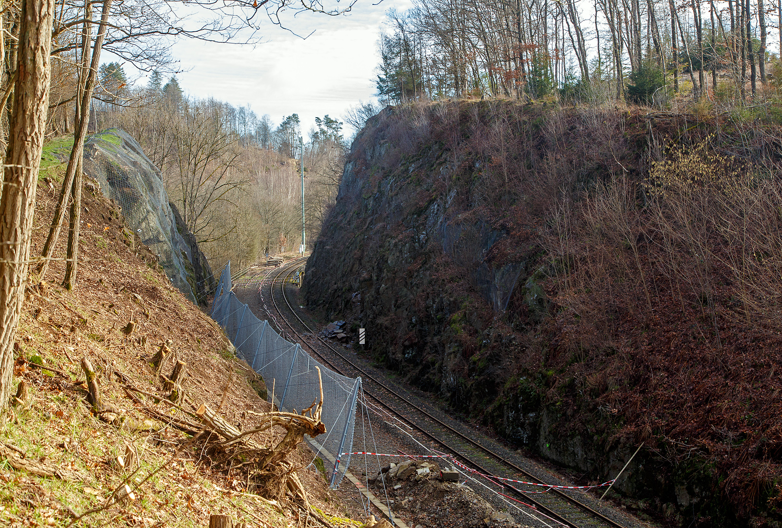 HLB Zug am 23.12.2022 auf der Hellertalbahn entgleist und die Strecke bleibt weiter lange, vermutlich bis Juni 2023, gesperrt...
Die Strecke der Hellertalbahn (KBS 462), beim Hp Königsstollen in Richtung Herdorf  (Hp Königsstollen) gesehen am 06.02.2023. Hier sieht man Tatsache das links beim alten Gleis bereits umfangreiche Hangsicherungsmaßnahmen stattgefunden haben. Rechts am aktiven Gleis sieht man das abgerutschte Material, welches am 23.12.2022 einen Triebwagen der RB 96 „Hellertalbahn“, den HLB VT 507, zur Entgleisung brachte. Verletzt wurde zum Glück niemand.

Derzeit muss man von einer Sperrung der Hellertalbahn bis zum Juni ausgehen. Ja, die Sicherheit geht vor!!! Aber ist wirklich keine kurzfristige Maßnahme möglich. Könnte man nicht einfach das aktive Gleis ins alte zweite Gleis verschwenken? 

Neben der Sperrung der Bahn, gibt es in Herdorf wegen Straßenbauarbeiten schon genug Probleme mit dem Umleitungsverkehr auf den Straßen. Hinzu kommt ab Anfang April ein weiteres Problem in der Verbindung zwischen Betzdorf und Herdorf, denn dann wird der vom Landesbetrieb Mobilität beauftragte Abriss und Neubau der Hellerbrücke in Herdorf beginnen. Die L284 soll dafür bis August gesperrt bleiben und in den ersten sechs Wochen auch die wichtige Umleitungsverbindung über die L285 nach Daaden.
