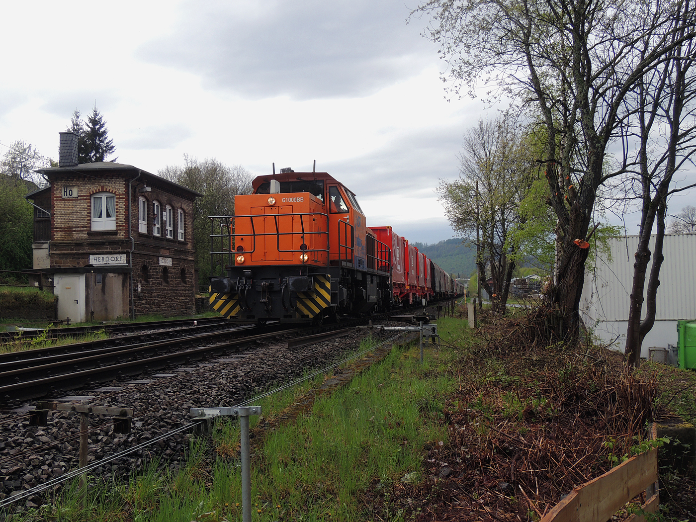 Hochbetrieb in Herdorf am 23 April 2025: 
Durch die vergangenen Osterfeiertage braucht es wohl wieder Nachschub. Die KSW (Kreisbahn Siegen-Wittgenstein) kommt im Sandwich mit einem sehr langen und somit schweren Coilzug, von via Betzdorf/Sieg kommend in Herdorf an. Gleich drauf geht es auf den KSW-Rangierbahnhof (Betriebsstätte FGE - Freien Grunder Eisenbahn). Übrigens die neuen m²-Güterwagen/Tragwagen der Gattung Uas 224.2 für Coiltransporte der DB Cargo AG sind hier immer mehr anzutreffen.

Vorne als Zuglok die KSW 44 (92 80 1271 004-4 D-KSW) eine MaK G 1000 BB und hinten nachschiebend die KSW 47 (92 80 1271 027-5 D-KSW), ex D 2 der HFM, eine Vossloh G 1000 BB.

Im Rbf wird der Zug geteilt, da er für die Weiterfahrt sonst zu lang wäre, und die KSW 44 zieht den ersten Teil weiter zu den Schäfer Werke KG am Pfannenberg in Neunkirchen-Salchendorf. 

Später kam dann noch die KSW 43 (92 80 1273 018-2 D-KSW), die asymmetrische Vossloh G 2000 BB, mit einem langen Coilzug von Duisburg an.