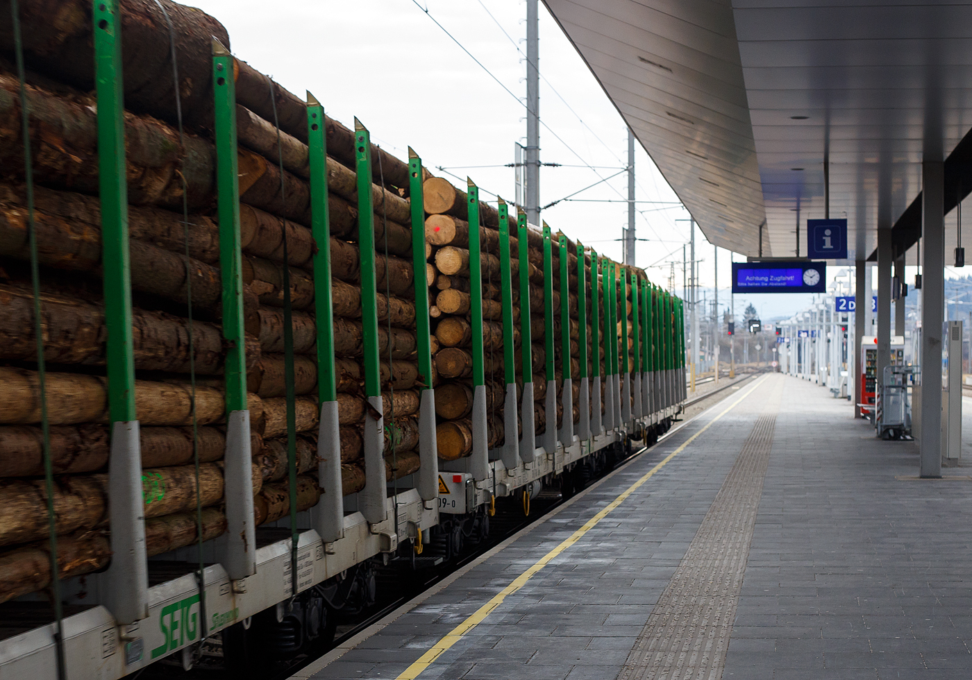 Im Zugverband am 14 Januar 2025 bei der Zugdurchfahrt im Bahnhof Attnang-Puchheim, ein mit Fichtenrundholz beladener vierachsiger Drehgestell-Flachwagen mit Rungen (Rungenwagen) D-SRA 4723 xxx-x der Gattung Snps „SFlexwood“ der SETG.

Die Salzburger EisenbahnTransportLogistik GmbH (SETG) investierte als erste Privatbahn Europa‘s in Neubau-Rungenwaggons. Das österreichische Eisenbahnunternehmen SETG hat gemeinsam mit dem slowakischen Hersteller Tatravagónka a.s. (in Poprad) einen neuen Holztransportwaggon namens Snps „SFlexwood“ entwickelt. Gegenüber herkömmlichen Rungenwagen verfügt die Neukonstruktion mit 8,8 m² über einen deutlich größeren Ladequerschnitt. Die Waggons sind mit Rungen ausgestattet, die sowohl Rundholz- als auch Schnittholztransport ermöglichen. Teile des Rungenschemels sind dazu im Wagenboden integriert, damit beim Schnittholztransport die gesamten Breite zur Verfügung steht. Die Sortimentslängen können 2,5 bis 17 m betragen und die Nutzlast liegt bei 68 t. Durch den Verzicht auf Stirnwände sollen sich bis zu 25% Fahrenergie einsparen lassen. Insgesamt hat die SETG 180 Einheiten des SFlexwood erhalten, remisiert bzw. einstellt sind sie in Deutschland als D-SRA 4723 xxx-x, die internationale Verwendungsfähigkeit ist TEN-CW. 

SFLEXWOOD ist der neue Standard-Holzwaggon: für unterschiedliche Holzlängen, Rund- und Schnittholz, kundenspezifische Zugslängen und maximal ökologisch.

Kenndaten:
Bei 17,20 m Ladelänge und Bauprofil ‚G2‘ waren letztendlich 8,8 m² Ladequerschnitt das Ergebnis detaillierter Planung. Dies stellt den größten Ladequerschnitt aller Rundholzwaggons in Europa dar. Über 68 Tonnen Nutzlast pro Waggon ergeben ein Ladungsgewicht pro Zug von max. 2.380 Tonnen. Je nach Holzbeschaffenheit lassen sich auf einem SFLEXWOOD-Zug somit bis zu 2.500 Festmeter (fm) verladen. Oder bis zu 4.200 Kubikmeter (m³) Schnittholz pro Zug. Soviel wie noch nie auf Zügen in Zentral- und Osteuropa auf Ganzzügen für den Holztransport Platz gefunden hat. Der SFLEXWOOD ist universell in den meisten Ländern Europas einsetzbar – eine wichtige Voraussetzung im flexiblen Holz-Transportmarkt. Die kompakte Länge des SFLEXWOOD-Waggons ermöglicht flexible, kundenspezifische Zuglängen, weniger Rangierbewegungen bei Be- und Entladung und damit eine optimale Auslastung der oft kurzen Lade-/Entladegleise.

Die Wagenkonstruktion ist für eine Achslast von 25 t aus der Sicht der Festigkeit ausgelegt. Der Wagen ist mit einem 70 mm dicken Holzboden und einer Ladekante ausgestattet, die den Wagenfußboden vor Beschädigungen schützt. Der Fußboden erfordert nur geringen Aufwand. Alle Bedienelemente befinden sich unter dem seitlichen Längsträger und sind so vor ungewollten Beschädigungen während der Handhabung mit dem Ladegut geschützt.

Bahngeschichte geschrieben:
Zum ersten Mal seit dem zweiten Weltkrieg hat in Europa eine Privatbahn in den Neubau von Waggons für den Holztransport investiert. Die SETG stärkt damit in ihrem Kernsegment, dem Transport von Forstprodukten, ihre Kompetenz und bietet ihren Kunden ab sofort den maximal größten und maximal flexibelsten Holz-Ganzzug an: SFLEXWOOD.

TECHNISCHE DATEN der SFLEXWOOD-Wagen:
Hersteller: Tatravagónka a.s., in Poprad (Slowakei)
Baujahr: ab 2023
Spurweite: 1.435 mm (Normalspur)
Länge über Puffer: 18.440 mm
Drehzapfenabstand: 12.900 mm
Achsabstand im Drehgestell: 1.800 mm
Laufraddurchmesser: 920 mm (neu) 
Drehgestelltyp: Y25 Ls-K
Ladefläche: 46,8 m²
Ladelänge: 17.200 mm
Höhe der Ladeebene über SOK: 1.260 mm
Anzahl der Rungenpaare: 10
Rungenhöhe: 2.410 mm
Eigengewicht: ca. 22,0 t
Max. Zuladung bei Lastgrenze S: ca. 68,0 t (ab Streckenklasse D)
Max. Geschwindigkeit: 100 km/h (beladen) / 120 km/h (leer)
Max. Radsatzlast: 22,5 t
Intern. Verwendungsfähigkeit: TEN / CW