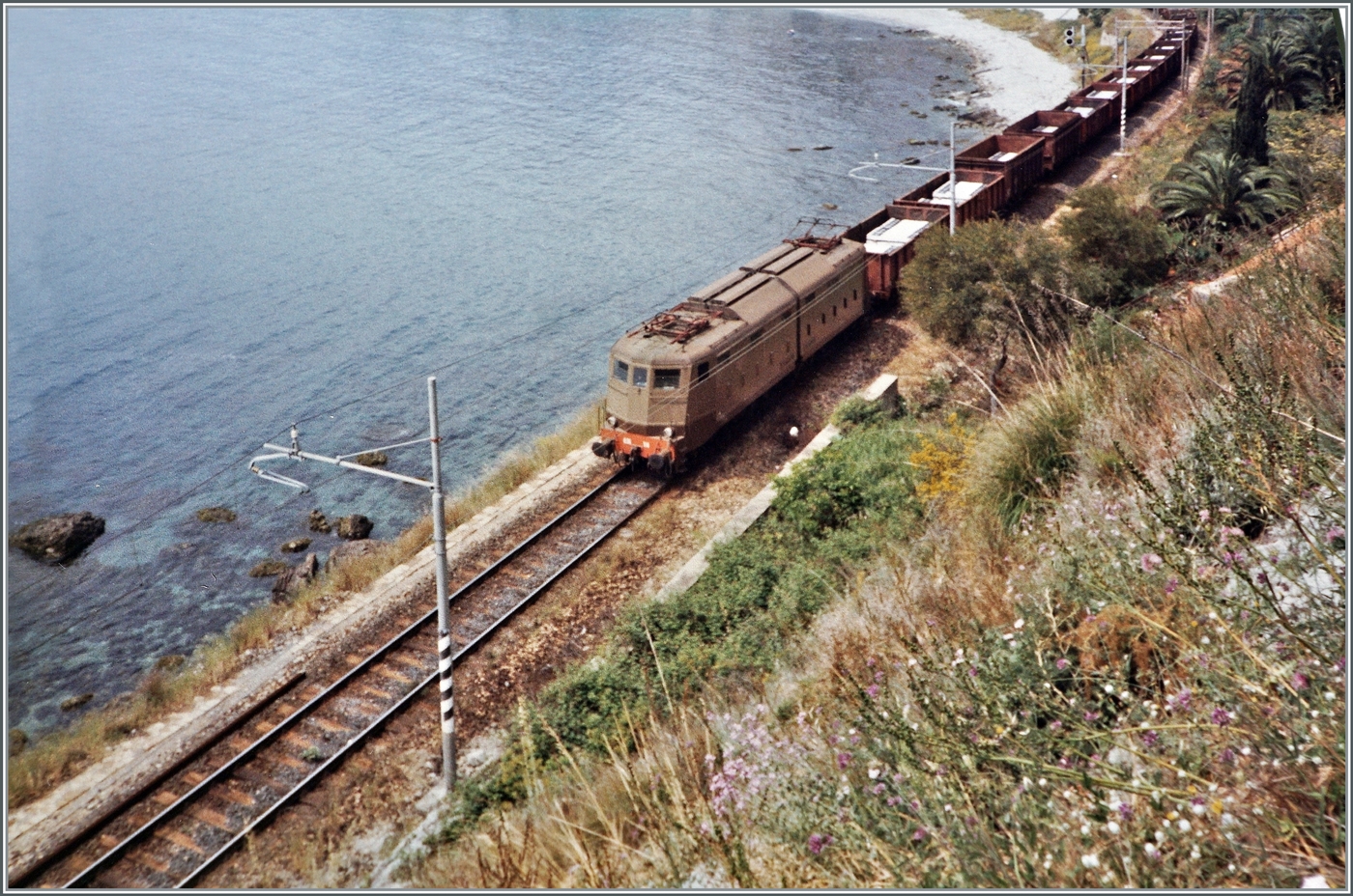 Kurz nach dem Bahnhof von  Taormina-Giardini ist diese FS 636 mit einem Güterzug auf dem Weg in Richtung Messina. 

Analog Bild vom Mai 1988