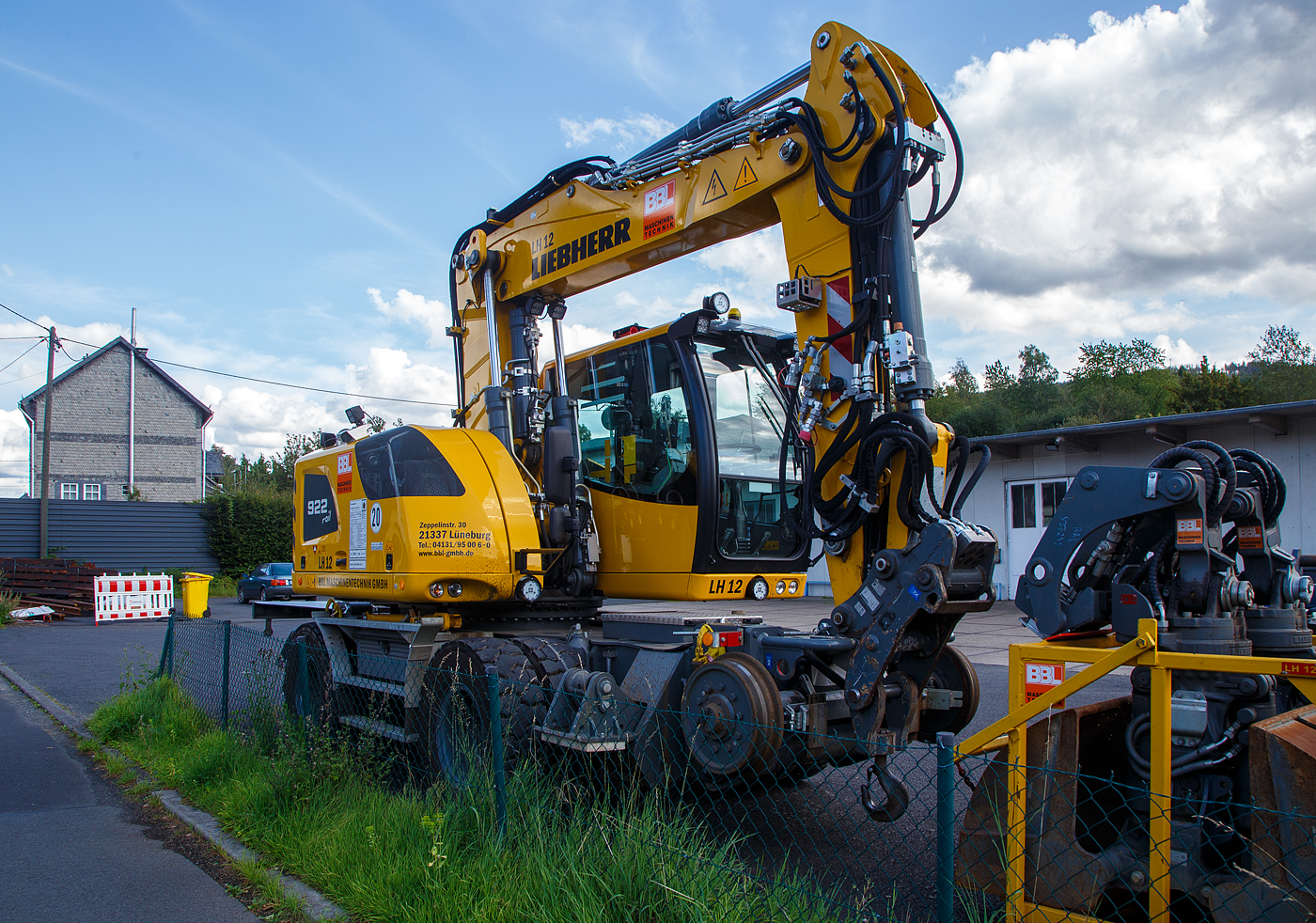 Liebherr Zweiwegebagger A 922 Rail Litronic (Baureihe 1190) mit Abstützpratzen, interne Nr. LH 12 der BBL Maschinentechnik GmbH (Lüneburg), eigestellt durch die SES Aus- und Fortbildung e.K. (Horst / Holstein) unter der Kleinwagen Nr. D-SESAF 99 80 9904 303-1, abgestellt am 26.08.2023 in Herdorf (Ostweg) beim Lokschuppen der KSW, Betriebsstätte FGE -Freien Grunder Eisenbahn.

Der ZW-Bagger wurde 2022 von Liebherr unter der Fabriknummer KLHZ1509JZK137327 gebaut.

Der A 922 Rail Litronic kann als Zweiwegemaschine wahlweise auf der Straße oder auf Eisenbahnschienen eingesetzt werden. An beiden Seiten des Unterwagens ist das Schienenfahrwerk angebracht. Während des Aufgleisens bringt das Schienenfahrwerk die Bereifung auf Schienenniveau, wobei die inneren Räder der Zwillingsbereifung den Fahrantrieb auf der Schiene übernehmen.

TECHNISCHE DATEN:
Spurweite: 1.435 mm
Länge über Puffer: 6.400 mm
Achsabstand (Schiene): 5.700 mm
Laufraddurchmesser (Schiene): 500 mm (neu)
Eigengewicht: 24 t
Motorbauart: wassergekühlter 4Takt - 4-Zylinder-Reihendieselmotor mit Common-Rail-Einspritzsystem, Turbolader und Ladeluftkühlung
Motortyp: Liebherr D924 – FPT 
Motorhubraum: 4,5 Liter
Motorleistung: 120 kW / 163 PS
Höchstgeschwindigkeit (Hg): 19,9 km/h (in Kreuzungen und Weichen 10 km/h)
Zugkraft: 117 kN
Bremse: Kfz.-/SFE-Bremse und Wagonbremsanlage
Zul. Anhängelast: 120 t (ungebremst 40 t)
Zur Mitfahrt zugel. Personenzahl: 1 (und Fahrer)
Antrieb auf Schiene: Über Reibantrieb der Straßenreifen
Hinterer Schwenkradius: 2.000 mm
Max. Neigung: 40 ‰
Max. Gleisüberhöhung: 200 mm
