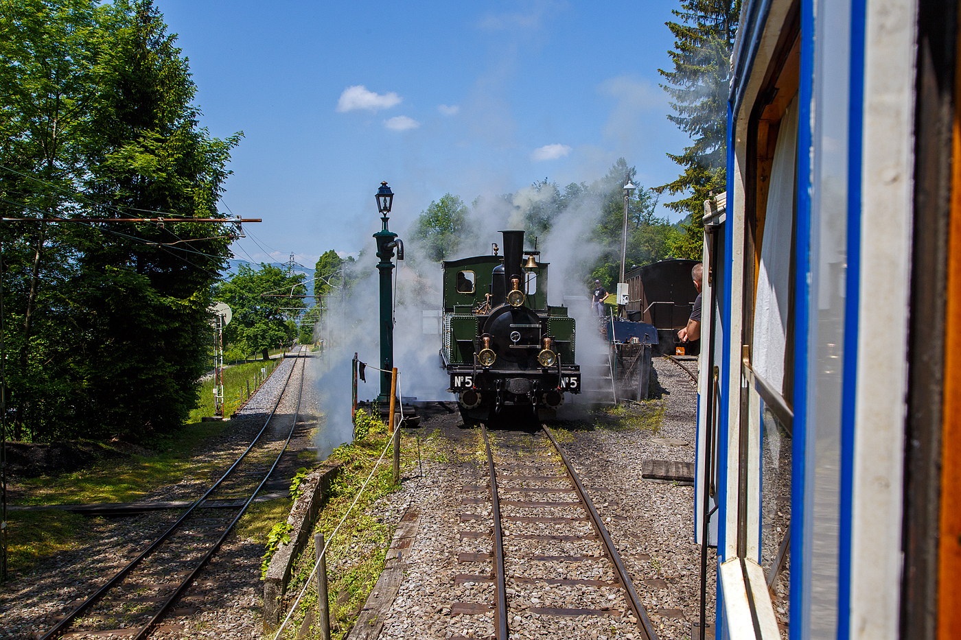 Museumsbahn-Romantik pur – Pfingsten 2023 (Samstag 27. bis Montag 29. Mai 2023) fand bei der Museumsbahn Blonay–Chamby das Schweizer Dampffestival 2023 / Festival suisse de la Vapeur 2023 statt.

Bei der Dampflok-Wartungsstelle der Museumsbahn Blonay–Chamby beim Museumsareal in Chaulin steht am 27.05. 2023 die G 3/3 LEB N° 5  Bercher  der Museumsbahn zum Kohlefassen. Links die Strecke 115 der MVR hinab nach Blonay, wir fahren mit dem ex MOB BCFe 4/4 11 rechts das Stichgleis zum Museum bzw. Depot hinauf.

Die ex LEB Nr. 5  Bercher  (Lausanne–Echallens–Bercher-Bahn) wurde 1890 von der Elsässische Maschinenbau-Gesellschaft Grafenstaden (später Société Alsacienne de Constructions Mécaniques) unter der Fabriknummer 4172 gebaut und an die Lausanne–Echallens–Bercher-Bahn geliefert. Die EMBG hatte auch zwei Jahre zuvor die baugleiche Nr. 2 geliefert. Die beiden dreiachsigen Tenderlokomotiven trugen die Hauptlast des Verkehrs, bis in den Jahren 1903 und 1905 zwei baugleichen Tenderlokomotiven, die G 3/3 6 „Gros-de-Vaud“ und G 3/3 7 „Talent „durch die Schweizerische Lokomotiv- und Maschinenfabrik (SLM) in Winterthur abgeliefert wurden. 

Von der YSteC konnte die LEB 1920/1921 die drei 1893 ebenfalls durch die EMBG gebauten Mallet-Lokomotiven G 2x2/2 Nr. 1 bis 3 gebraucht übernehmen. Nun waren die G 3/3 Nr. 2 und 5 nicht mehr gefragt. Während die G 3/3 2 „Échallens“ bereits 1929 verschrottet wurde (seit 1920 war sie bereits abgestellt), die G 3/3 Nr. 5  Bercher  hatte es da etwas besser, sie wurde 1934 an die Firma Energie de l’Ouest Suisse (EOS) für die Baustelle der Staumauer Grande-Dixence verkauf. Nach dem die Arbeiten 1935 erledigt sind geht sie bei der EOS außer Betrieb. Im Jahr 1939 verlässt die Schweiz und geht nach Vorarlberg in Österreich, zu einer Baufirma. Die Baufirma verschenkte 1967 die Lok und sie wurde, wie viele andere Dampflokomotiven zu dieser Zeit, auf einem Kinderspielplatz in der Stadt Feldkirch aufgestellt. Das Ausstellungsobjekt weckte die Aufmerksamkeit einiger Mitarbeiter der Museumsbahn Blonay–Chamby (BC), denen es gelang 1973 diese Lokomotive im Tausch gegen eine andere Lok zu erwerben.

Nach einer Aufarbeitung war die Lokomotive 1985 bis 2005 in Betrieb. Dann musste sie abgestellt werden. 2013/2014 wurde die Lokomotive ein zweites Mal durch die Museumseisenbahner aufgearbeitet. Seit dem Frühling 2015 ist die zweitälteste Schmalspur-Dampflokomotive der Schweiz, die älteste ist die G 3/4 1 „Rhätia  der Rhätischen Bahn (RhB), nach dem Abschluss der Revisionsarbeiten wieder in Betrieb.

TECHNISCHE DATEN der LEB G 3/3 N° 5  Bercher :
Baujahr: 1890
Spurweite: 1.000 mm
Achsformel: C
Länge über Puffer: 6.830 mm
Achsabstand: 1.800 mm (950mm / 850 mm)
Dienstgewicht: 20,4 t
Anzahl der Zylinder: 2
Zylindergröße: Ø 270 mm x 370 mm Kolbenhub
Treibraddurchmesser: 810 mm
Höchstgeschwindigkeit: 25 km/h
Stundenleistung: 150 PS
Kesselüberdruck: 12 bar
Kohlevorrat: 0,8 t
Wasservorrat: 2,2 m³

Die Lausanne–Echallens–Bercher-Bahn, abgekürzt LEB, französisch Chemin de fer Lausanne–Echallens–Bercher, ist eine meterspurige Privatbahn. Die knapp 24 Kilometer lange Strecke führt vom Stadtzentrum von Lausanne (Flon) durch die nördlichen Vororte und weiter nach Echallens und Bercher im Gros de Vaud, dem Waadtländer Hinterland. Die LEB ist eine moderne Vorortbahn, die in Lausanne teilweise unterirdisch verkehrt. Die Züge fahren alle 30 Minuten (zwischen Echallens und Bercher gibt es einige wenige Taktlücken am Vormittag). Werktags wird ein Viertelstundentakt bis Cheseaux angeboten. Von Montag bis Freitag verkehren in Lastrichtung einige beschleunigte Hauptverkehrszüge.