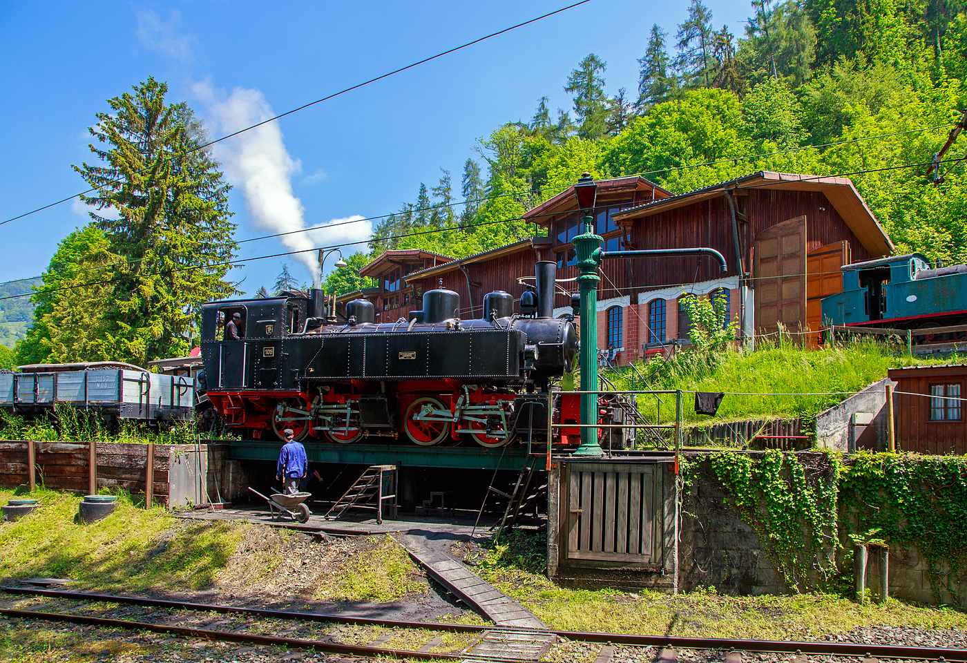 Museumsbahn-Romantik pur – Pfingsten 2023 (Samstag 27 bis Montag 29 Mai 2023) fand bei der Museumsbahn Blonay–Chamby das Schweizer Dampffestival 2023 / Festival suisse de la Vapeur 2023 statt.

Bei der Dampflok-Wartungsstelle der Museumsbahn Blonay–Chamby beim Museumsareal in Chaulin steht am 27. Mai 2023 die G 2x2/2 Mallet-Dampflok 105  Todtnau  der Museumsbahn Blonay–Chamby, ex SEG 105  Todtnau .  Links die Strecke hinab nach Blonay, rechts das Stichgleis zum Museum bzw. Depot.

Für den Einsatz auf den Meterspur-Strecken in Frankreich bestellten die Deutschen Heeresfeldbahnen bei der Maschinenbau-Gesellschaft Karlsruhe sieben Mallet-Dampflokomotiven. Aus Zeitgründen wurde keine zeitgemäße neue Serie entwickelt. Man nahm alte Konstruktionsunterlagen als Grundlage. Die Auslieferung erfolgte im August 1918. Bevor die Maschinen HK 94 bis HK 100 (HK = Heeresprüfkommission für Feldbahnen) ihren Einsatzort erreichten, war der I. Weltkrieg (Waffenstillstand von Compiegné am 11. November 1918) jedoch schon beendet. Da sie nicht mehr von den Heeresfeldbahnen benötigt und nicht zum Reparationsgut zugeordnet wurden, übernahm sie das Reichsverwaltungsamt. Dieses verkaufte in den Jahren 1919/1920 die Loks.

Die Lok wurde 1918 von der Maschinenbau-Gesellschaft Karlsruhe unter der Fabriknummer 2051gebaut und von der Heeresprüfkommission für Schmalspurbahnen abgenommen als Lok „HK 95“ abgenommen, wegen dem Kriegsende kam sie auf den Heeresfeldbahnen nicht mehr zum Einsatz. So wurde sie 1919 an die Kleinbahn Voerde-Haspe–Breckerfeld als HVB 28 verkauft. Die Kleinbahn Voerde-Haspe–Breckerfeld wurde elektrifiziert, und die  Nr. 28  wurde 1925 an die Zell-Todtnau-Eisenbahn (in der Nähe von Freiburg) der Süddeutsche Eisenbahn-Gesellschaft (SEG) abgegeben, wo sie die  Nummer 105  -  Todtnau  erhielt. Sie blieb bis zur Streckenstillegung der Linie im Jahre 1968 im Schwarzwald und ging gleich drauf an die Museumsbahn Blonay – Champy.
Es ist noch eine Schwesterlok erhalten geblieben, es ist die 99 5906 der HSB.

Konstruktion:
Das hintere Triebwerk mit den Hochdruckzylindern ist fest im Blechrahmen gelagert. Das vordere Triebwerk mit den Niederdruckzylindern ist mit einem Königszapfen mit dem hinteren Triebwerk verbunden, der genietete Kessel liegt mit Gleitplatten auf ihm auf. Seitliche Blattfedern halten das Triebwerk in einer mittigen Stellung. Beide Triebwerke haben einen Innenrahmen.

Der Dampf wird erst zu den hinteren Zylindern geleitet, von dort gelangt er über flexible Leitungen in die vorderen Zylinder. Alle Zylinder verfügen über Flachschieber und außenliegende Heusinger-Steuerung mit Hängeeisen. Die Loks verfügen über eine Wurfhebel-Handbremse und eine Dampfbremse als Zusatzbremse. Je nach Bahn wurden später Saugluft- oder Druckluftbremse als Zugbremse nachgerüstet. Auf dem Kessel sitzen zwei Sanddome, einer für jedes Triebwerk.

TECHNISCHE DATEN:
Hersteller Maschinenbau-Gesellschaft Karlsruhe (MBK)
Baujahr: 1918
Betriebsgattung: K 44.9
Kurzbezeichnung: B' B n4vt
Spurweite: 1.000 mm
Kurzbezeichnung: B' B n4vt
Länge über Puffer: 9.400 mm
Höhe über SO: 3.800 mm
Achsstand im Triebwerk: 1.400 mm
Treibraddurchmesser: 1.000 mm
Leergewicht: 28,5 t
Dienstgewicht: 34,4 t
Höchstgeschwindigkeit: 30 km/h
indizierte Leistung: 200 kW (270 PS)
Anfahrzugkraft: 47,76 kN
kleinster befahrbarer Gleisbogen: 50 m
Kesselüberdruck: 12 bar
Kohlevorrat : 1,1 t
Wasservorrat: 3,6 m³
Zylinderanzahl: 4
Zylinderdurchmesser: 280 mm (HD) / 425 mm (ND)
Kolbenhub: 500 mm
Bremse: Knorrbremse m. Z., Wurfhebel-Handbremse

Geschichte der Mallet-Lokomotiven:
Der zunehmende Verkehr auf schmalspurigen Eisenbahnen erschloss Mallet ein anderes Wirkungsfeld. Diese Bahnen benötigten stärkere und damit größere Maschinen, als es die engen Kurven der Schmalspurstrecken zuließen. Die einzige Lösung schienen hier Lokomotiven mit schwenkbaren Fahrwerken zu sein. Dazu waren bereits die Bauarten von Fairlie und Meyer verbreitet, die schwenkbare Maschineneinheiten verwendeten. Die einzelnen Einheiten wurden mit Dampf über flexible Verbindungen gespeist, die sich jedoch stets als Schwachpunkt der Maschinen erwiesen. Mallet entwickelte stattdessen eine Bauart mit zwei Fahrwerken, von denen nur das vordere, unter der Rauchkammer befindliche Fahrwerk schwenkbar gelagert war, während der Kessel fest auf dem anderen Fahrwerk ruhte. Damit reduzierte sich die Zahl der flexiblen Verbindungen um die Hälfte. Der wesentliche Unterschied der Konstruktion von Mallet im Vergleich zu den Bauarten Fairlie und Meyer war aber die perfekte Anwendung eines Verbundtriebwerkes. Der Frischdampf wird zunächst zu den Hochdruckzylindern des fest gelagerten Fahrwerks geleitet und nach dem Auslass in die Niederdruckzylinder des vorderen beweglichen Fahrwerks. Die dorthin führende bewegliche Dampfleitungsverbindung war wegen des geringeren Drucks besser beherrschbar als bei reiner Frischdampf-Versorgung. Diese Bauart ließ Mallet sich 1884 patentieren.

Dampflokomotiven haben im Allgemeinen zwei Arbeitszylinder, die Mallet-Loks besitzen diese Einrichtungen doppelt, also 4 Zylinder mit zugehörigen Triebwerksgruppen. Der Abdampf der ersten ist gleichzeitig der Arbeitsdampf der zweiten Zylindergruppe.

Schweizerische Bauartbezeichnung G2 x 2/2, Deutsche Reichsbahn Baureihe 99.590

Mallet-Lokomotive B'B n4vt
- B'B = Dampflokomotive mit 2 Triebwerken, das erste davon beweglich gelagert, zu je 2 Treibachsen
- n4 = Naßdampf und 4 Zylinder
- v = Verbundwirkung zwischen den Hoch- und Niederdruck-Zylindern
- t = Brennstoff und Wasservorräte werden auf der Lokomotive mitgeführt
- (in neuerer Schreibweise wird häufig das  t  weggelassen.
- Bei Angaben ohne  t  handelt es sich dann immer um eine Tenderlok, im Gegensatz dazu  T  = Schlepptenderlok).
