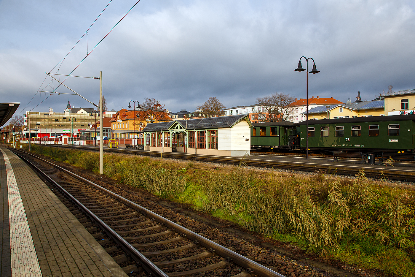 Radebeul Ost den 07.12.2022:
Blick vom Normalspurigen DB Bahnhof auf den Schmalspur Bahnhof der Lößnitzgrundbahn der SDG - Sächsische Dampfeisenbahngesellschaft mbH, mit dem schönen Wartehäuschen am Bahnsteig. Mit der 750 mm Schmalspurbahn, kann man mit Dampfzügen die 16,5 km lange Strecke von Radebeul Ost über Moritzburg nach Radeburg fahren

Wobei nach der deutschen Wiedervereinigung und der folgenden Bahnreform, die Deutschen Bundesbahn und Deutsche Reichsbahn wurden zum 01. Januar 1994 zur Deutsche Bahn AG vereinigt, gehörten  Bahnhof und die Schmalspur Bahn, bis Juni 2004 zur DB AG. Im Juni 2004 ging die Strecke gemeinsam mit der Weißeritztalbahn an die BVO Bahn GmbH (seit 2007 dann SDG - Sächsische Dampfeisenbahngesellschaft). Die SDG seit Anfang 2019 den Verkehrsverbünden Mittelsachsen (VMS) 1/3 und Oberelbe (VVO) 2/3.