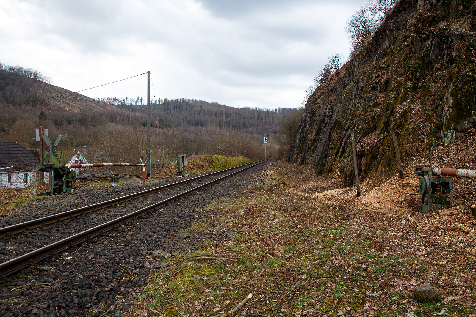 Stndig geschlossene alte Schranke (ehemalige Anrufschranke) bei km 87,8 (bei Herdorf-Sassenroth) der Hellertalbahn (KBS 462 / Strecke 2651), hier am 18.03.2023. Bis 1987 war der Abschnitt Betzdorf–Herdorf noch zweigleisig. 

Auch wenn hier mindestens bis zum kleinen Fahrplanwechsel im Juni 2023, wegen dem Felsstutz am 23.12.2022, kein Zug zwischen Betzdorf und dem Hp Knigsstollen (Herdorf) fhrt, ist und wird die Strecke nun gut freigeschnitten.