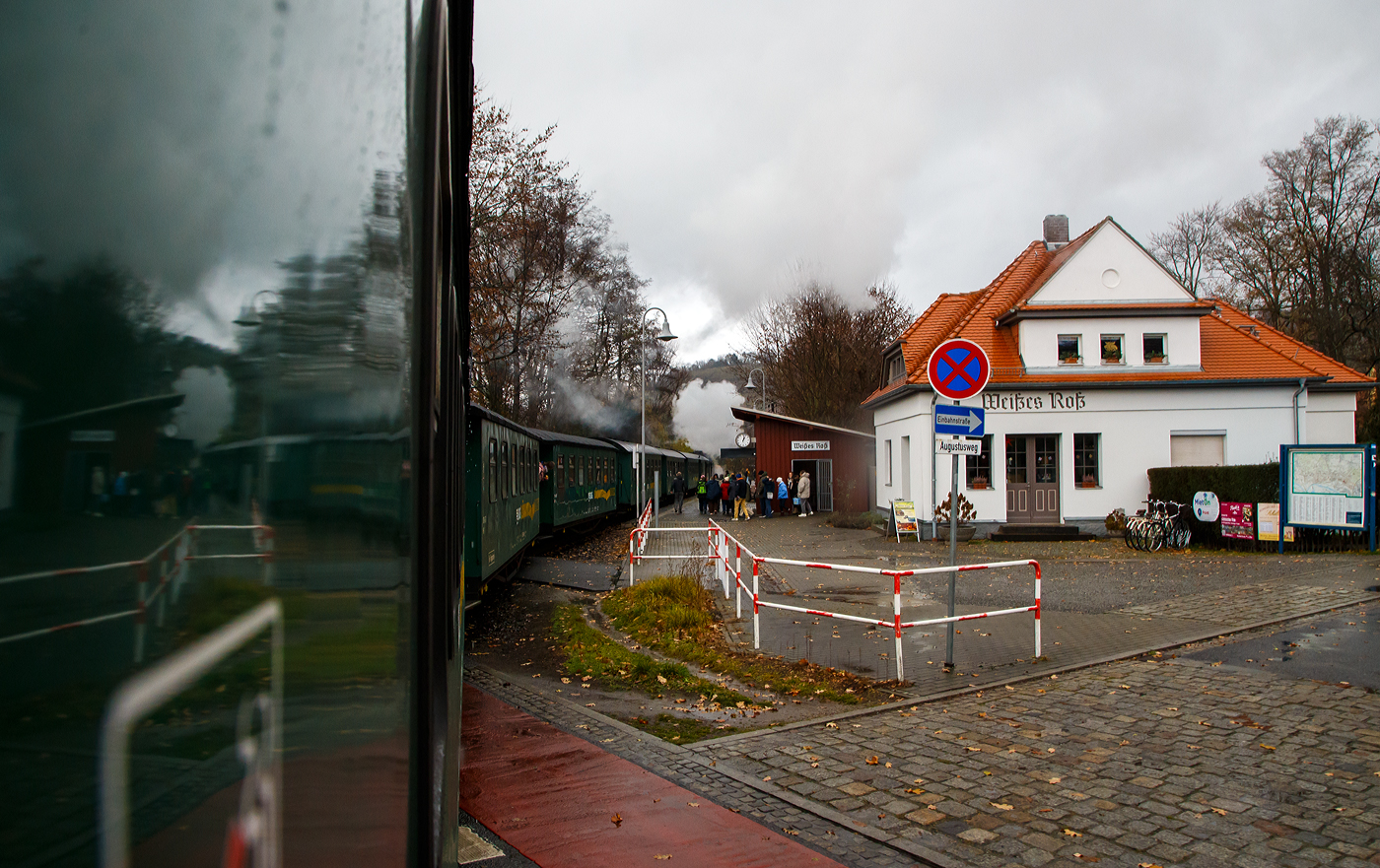 Unterwegs mit dem „Lößnitzdackel“  bzw. mit der Lößnitzgrundbahn der SDG - Sächsische Dampfeisenbahngesellschaft mbH, erreicht unser Dampfzug, gezogen von der sächsischen VII K (Altbau) 99 1761-6, nun am 07.12.2022 den Haltepunkt Weißes Roß (bei km 1,6), wir im letzten Wagen befinden uns noch am Bahnübergang Bü 1,5 - Meißner Straße in Radebeul.

Die Schmalspurbahn Radebeul Ost - Moritzburg - Radeburg ist eine sächsische Schmalspurbahn in der Spurweite von 750 mm außerhalb der sächsischen Landeshauptstadt Dresden. Für die Strecke wird heute auch die 1998 vergebene Marketingbezeichnung Lößnitzgrundbahn verwendet. Umgangssprachlich wird sie dagegen meist als Lößnitzdackel (kurz auch Dackel) oder früher Grundwurm bezeichnet.

Die in den Jahren 1911/1913 errichtete und heute denkmalgeschützte Bahnstation „Weißes Roß“ liegt nahe der Meißner Straße, wo sich die Schmalspurbahn Radebeul–Radeburg (Lößnitzgrundbahn – KBS 509) mit der Dresdner Straßenbahnlinie 4 kreuzt.

Die „Station“ besteht aus einem massiven, verputzten Bahnwärterhaus mit Fahrkartenschalter und Warteraum sowie einer nahebei gelegenen hölzernen Wartehalle. Das Bahnwärterhaus wurde 1913 durch die Königlich Sächsische Staatseisenbahnverwaltung errichtet. Es ist ein eingeschossiger, massiver Putzbau auf einem Bruchsteinsockel mit einem niedrigen Anbau, das Walmdach ist mit Ziegeln gedeckt, darin zwei Dachausbauten mit hohem Dreiecksgiebel. Die Wartehalle ist ein halboffenes, verbrettertes Fachwerk mit Pultdach.