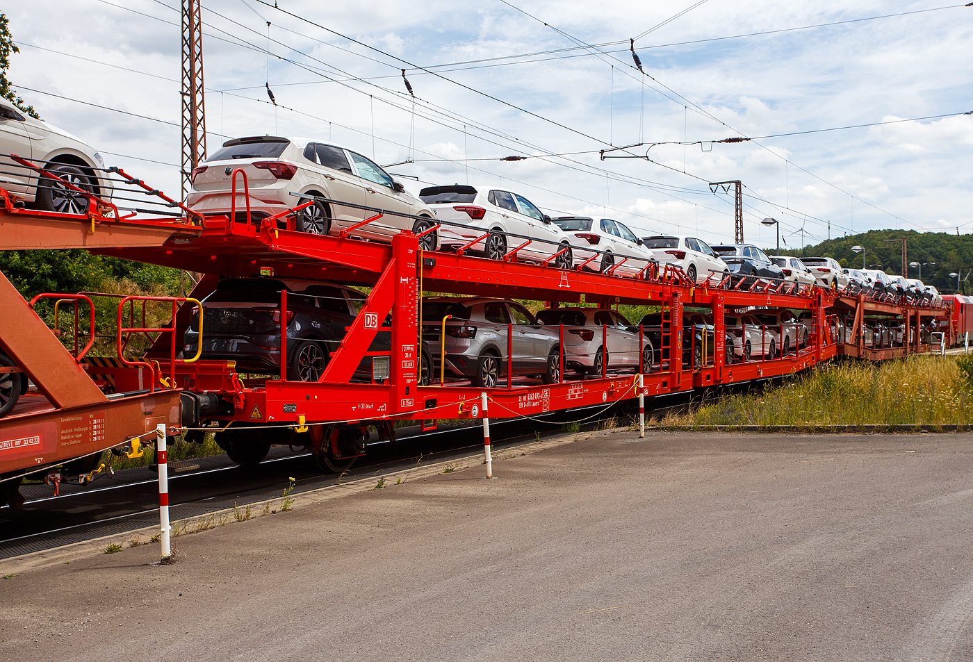 Vierachsiger (2 x zweiachsiger) Doppelstock-Autotransportwagen, 25 80 4363 493-4  D-ATG, der Gattung Laaers 560.2, der DB Cargo Logistics GmbH (ex DB Schenker ATG)  am 19 Juli  2024 im Zugverband bei der Zugdurchfahrt in Rudersdorf (Kreis Siegen), hier beladen mit VW PKW´s aus der „Stadt des KdF-Wagens bei Fallersleben“ (ab 1945 Wolfsburg).

Der Wagen wurde 201_ von der damaligen DB Waggonbau Niesky GmbH gebaut.

Diese Waggons haben zwei Ladeebenen und sind für den europaweiten Transport geeignet. Sie werden für den internationalen Transport von PKWs, SUVs und Vans eingesetzt und bieten maximale Flexibilität durch eine stufenlos verstellbare obere Ladeebene. Aufgrund der hohen Lastgrenze (bis 34 t) ist der Transport von besonders schweren Fahrzeugen der genannten Typen möglich.

Damit sowohl ein typenreiner Transport als auch eine Mischverladung in den unterschiedlichen Lademaßen möglich ist, kann die obere Ladeebene hinsichtlich der Transportstellungen stufenlos eingestellt werden.

Durch die Entwicklung eines veränderten Ladungssicherungssystems wurde den Kundenanforderungen nach optimierten Transportmöglichkeiten für Fahrzeuge mit niedrigerer Bodenfreiheit Rechnung getragen.

TECHNISCHE DATEN:
Gattung: Laaers (Bauart 560.2)
Erstes Baujahr der Wagengattung: 2007
Spurweite: 1.435 mm
Anzahl der Achsen: 4 (2 x 2)
Länge über Puffer : 31.000 mm
Achsabstände: 10.000 mm / 5.160 mm / 10.000 mm
Laufraddurchmesser (neu): äußere 840 mm und mittlere 730 mm
Ladelänge : 30.070 mm (unten) / 30.550 mm (oben)
Ladelänge waagerechter Teil untere Ebene: 19.400 mm
Ladebreite : 2.950 (unten) / 2.750 mm (oben)
Höchstgeschwindigkeit: 100 km/h (120 km/h leer)
Eigengewicht: 30.500 kg
Max. Zuladung bei Lastgrenze S: 33,5 t (ab Streckenklasse B, bei A 32,0 t)
Max. Zuladung der Ladeebenen: unten und oben jeweils max. 18 t
Max. Gewicht je Pkw: 2.800 kg (Radlast max. 1 t)
Anzahl der Radvorleger: 64
Höhe Geländer oben: 600 mm
Kleinster befahrb. Gleisbogenhalbmesser: 75 m
Bremse: KE-GP-A (K)
Bremssohle: Jurid 816 M
Handbremse: Ja
Intern. Verwendungsfähigkeit: TEN-GE

Der große Unterschied zwischen den Laaers-Wagen der Bauart 560.2 (wie hier) und der Bauart 560.1 sind das Lastgrenzenraster (Max. Zuladung), zudem ist die Bauart 560.2 meist 500 kg leichter.