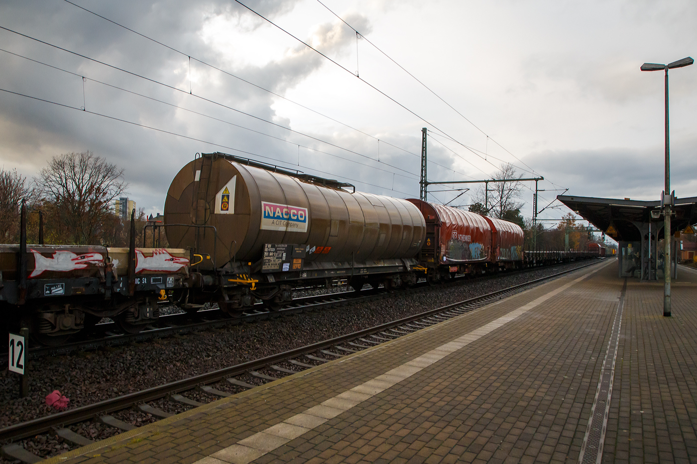 Vierachsiger 75 m³ Drehgestell-Kesselwagen, 37 80 7931 640-2 D-VTGCH, der Gattung Zacens, der VTG Rail Europe GmbH (ein ehem. NACCO Waggon) am 07.12.2022 im Zugverband bei einer Zugdurchfahrt im Bahnhof Dresden-Strehlen. Im Jahr 2018 hat die VTG sämtliche Anteile der CIT Rail Holdings (Europe) SAS übernommen, zu der auch die die NACCO-Gruppe mit 11.000 Güterwagen gehörte. 

Das Ladegut ist hier Natriumcyanid Lösung, was auch die Gefahrguttafel (66/2031) zeigt: (oben) Gefahrgutnummer 66 = sehr giftiger Stoff / (unten) UN-Nummer 3414 = Natriumcyanid Lösung. Natriumcyanid ist das Natriumsalz der Blausäure (HCN). Bei Raumtemperatur ist es ein farbloses, hygroskopisches kristallines Pulver, das leicht bittermandelartig riecht. In Gegenwart von Säuren zersetzt es sich in das hochtoxische Gas Blausäure (Cyanwasserstoff). 

Verwendung:
Natriumcyanid wird zusammen mit Kaliumcyanid zur Gewinnung von Gold, Silber und anderen Metallen verwendet. In der Galvanotechnik wird es für verschiedene cyanidische Bäder genutzt. Bei der Metallbearbeitung kommt geschmolzenes Natriumcyanid zum Härten bestimmter Stahlsorten (Einsatzstähle) zum Einsatz.

Die Bedeutung der Gattungs- und Kennbuchstaben (hier Zacens):
Z - Kesselwagen für den Transport von flüssigen oder gasförmigen Erzeugnissen
a - mit vier Radsätzen
c - mit Entladung unter Druck
e - mit Heizeinrichtung
n - mit vier Radsätzen höchste Lastgrenze über 60 t
s - Höchstgeschwindigkeit 100 km/h (beladen)