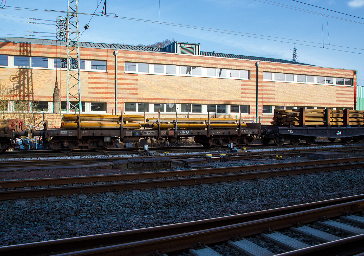 Vierachsiger Drehgestell-Flachwagen mit Drehrungen und Stirnwandklappen, jedoch ohne Seitenborde, 31 80 3961 943-8 D-DB, der Gattung Rmms 664, der DB Cargo AG, beladen mit Rundstahl, am 12. März 2017 im Zugverband auf dem Anschlussgleis der Deutschen Edelstahlwerke GmbH, zuvor Edelstahlwerke Südwestfalen, in Siegen-Geisweid

Mit einer Ladelänge von 12,80 m dienen diese Wagen mit aufgeklappten Ladeschwellen zur Beförderung von schweren langen Erzeugnissen der Eisen- und Stahlindustrie (wie Walzprofile) und anderen sperrigen und schweren Gütern. Mit eingeklappten Ladeschwellen, also mit ebener Ladefläche, eignet er sich auch für die Beförderung von schweren Kettenfahrzeugen. Vor den umlegbaren Stirnwänden sind je zwei absenkbare Rungen angeordnet. Der Wagen kann mit umgelegten Stirnwänden und abgesenkten Rungen gefahren werden. Die Höhe der umgelegten Stirnwände über FO beträgt 38 mm. An den Längsseiten hat der Wagen je 6 Drehrungen. Der Fußboden besteht aus Kiefernbohlen mit den Abmessungen 70 x 180 mm. Er kann eine Radlast von 5,0 t aufnehmen. Im Fußboden sind 6 geteilte, klappbare Ladeschwellen eingebaut.

Die an den Stirnseiten angeordneten Überfahrklappen gestatten abgeklappt das Durchfahren von Gleisbögen mit mindestens 150 m Halbmesser. Die Überfahrklappen liegen im abgeklappten Zustand auf 4 Konsolen auf. In senkrechter Stellung werden sie durch je 2 am Kopfstück angeordneten Fallrungen gehalten.

Die Wagen haben eine Klotzbremse mit stufenlos, selbsttätiger Lastabbremsung. Die Bremskraft nach dem minder belasteten Drehgestell gesteuert. Das Steuerventil ist im Wagenuntergestell angeordnet.

TECHNISCHE DATEN:
Spurweite: 1.435 mm (Normalspur)
Gattung/Bauart: Rmms 664
Erstes Baujahr: 1968
Anzahl der Achsen: 4 in 2 Drehgestellen
Länge über Puffer: 14.040 mm
Drehzapfenabstand: 9.000 mm
Achsabstand im Drehgestell: 1.800 mm
Ladelänge: 12.644 mm
Ladebreite: 2.904 mm
Ladefläche: 36,0 m²
Fußbodenhöhe über SO: 1.235 mm
Höchstgeschwindigkeit: 100 km/h (beladen) / 120 km/h (leer)
Eigengewicht: 21.000 kg
Maximale Ladegewicht: 59,0 t (ab Streckenklasse C)
Laufraddurchmesser: 920 mm (neu)
Kleinster bef. Gleisbogenradius: 35 m
Bauart der Bremse: KE-GP-A max. 56 t (LL)
Bremssohle: IB 116 (C952-1)
Handbremse: Fbr (wirkt auf beide Drehgestelle)
Internationale Verwendungsfähigkeit: RIV
