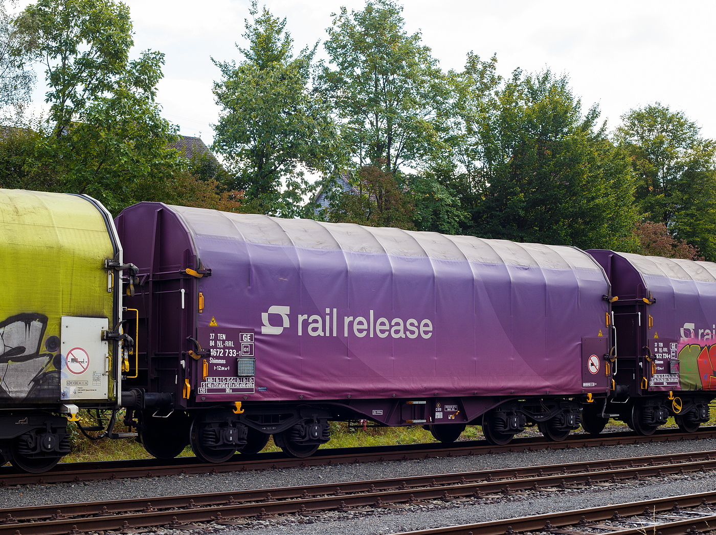 Vierachsiger Drehgestell-Flachwagen mit verschiebbarem Planenverdeck und Lademulden fr Coiltransporte, 37 84 4672 733-1 NL-RRL, der Gattung Shimmns, der niederlndischen Vermietungsfirma Railrelease B.V. (Rotterdam), am 15 September 2024 im Zugverband, auf dem KSW Rbf in Herdorf (Betriebssttte Freien Grunder Eisenbahn - NE 447).

TECHNISCHE DATEN:
Spurweite: 1.435 mm (Normalspur)
Achsanzahl: 4 (in 2 Drehgestelle)
Lnge ber Puffer: 12.040 mm
Lnge der Ladeflche: 10.800 mm
Drehzapfenabstand: 7.000 mm
Achsabstand im Drehgestell: 1.800 mm
Laufraddurchmesser: 920 mm (neu)
Eigengewicht: 20.200 kg
Hchstgeschwindigkeit: 100 km/h (beladen) / 120 km/h (leer)
Maximales Ladegewicht: 69,8 t (ab Streckenklasse D4)
Kleinster bef. Gleisbogenradius: 35 m
Bauart der Bremse: FREIN KE-GP-A max. 59 t (K)
Bremssohle: Cosid 810
Handbremse: an einem Drehgestell
Intern. Verwendungsfhigkeit: TEN GE / G1