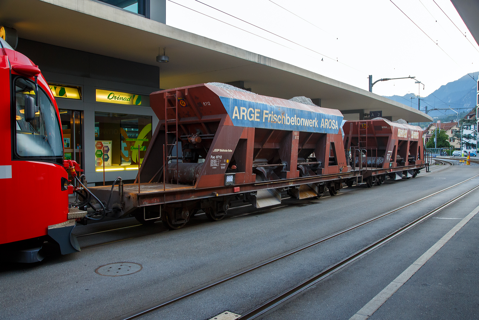 Vierachsiger Drehgestell-Schotterwagen (Schwerkraftentladewagen) RhB Fac  8712 (der Serie 8701 – 8712), eingereiht in einen RhB PmG (Personenzug mit Güterbeförderung) nach Arosa, geführt von dem ALLEGRA-Zweispannungstriebzug RhB ABe 8/12 -3507 „Benedetg Fontana“ am 07 September 2021 am Bahnhofvorplatz in Chur.

Diese Wagen wurden 1968 und 1971 von der Firma Josef Meyer in Rheinfelden gebaut. Mit den Schwerkraftentladewagen transportiert die RhB problemlos Ihre Schüttgüter wie Kies, Sand etc. auf der Schiene durch Graubünden. Ein rascher Verlad und Entlad spart Zeit und Geld und mit 33 – 34 Tonnen Ladung ist es eine gewichtige Alternative zum Straßentransport. Die Wagen haben je zwei Entladungsöffnungen längsseits, die Auslaufmenge ist dosierbar.

TECHNISCHE DATEN:
Spurweite: 1.000 mm
Länge über Puffer: 12.500 mm
Breite über Alles: 2.550 mm
Höhe über SOK: 3.360 mm
Drehzapfenabstand: 7.000 mm 
Achsabstand im Drehgestell: 1.400 mm
Laufraddurchmesser: 750 mm (neu)
Breite der Entladeöffnungen: 2 x 1.232 mm
Eigengewicht: 14.100 kg
Ladegewicht: max. 34 t
Ladevolumen: 22 m³
Breite der Entladeöffnungen: 2 x  1.232 mm