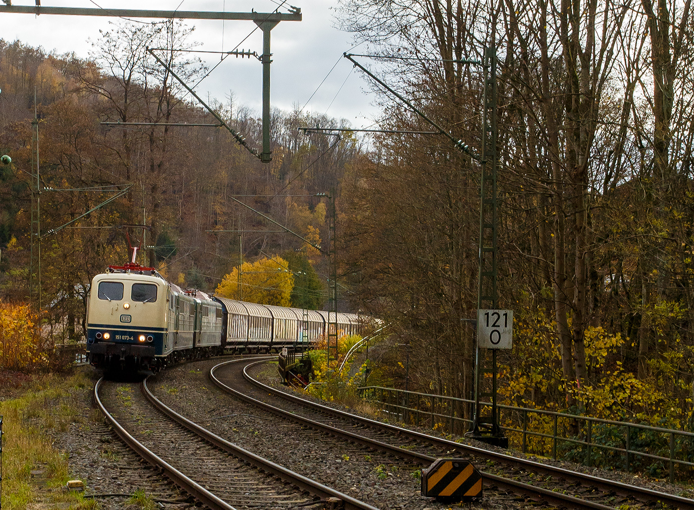 Vor dem sogenannten  Henkelzug  (Langenfeld/Rhld. nach Gunzenhausen) gleich drei Loks der BR 151 der BayernBahn GmbH (Nördlingen). Geführt von der 151 073-4 (91 80 6151 073-4 D-BYB) in ozeanblau/beige, dahinter die beiden kalten, jeweils in der ursprünglichen Farbgebung chromoxidgrün, 151 038-7 (91 80 6151 038-7 D-BYB) und die 151 016-3 (91 80 6151 016-3 D-BYB). 

Die BayernBahn ist übrigens eine Tochtergesellschaft des Bayerischen Eisenbahnmuseums e.V.. Sie besitzt z.Z. 6 dieser mit 5.982 kW leistungsstarken und bis zu 120 km/h schnellen Maschinen der Baureihe 151. Wenn ich hier die Lok in „chromoxidgrün“ sehe, dann fühle ich mich gleich in meine Kindheit zurückversetz. Oft konnte ich sie am Bahnübergang durchfahren sehen. 

Die Lebensläufe der Loks:
Die 151 073-4 wurde 1974 von Henschel in Kassel unter der Fabriknummer 31816 gebaut und in der Farbgebung ozeanblau/beige an die Deutsche Bundesbahn ausgeliefert. Zum 01.01.2017 wurden je 100 sechsachsige elektrische Altbau-Lokomotiven der Baureihen 151 und 155 an den Lokvermieter Railpool verkauft, so auch diese. 2019 wurde die 151er an die BayernBahn GmbH in Nördlingen verkauft. 

Die 151 038-7 wurde 1974 von der Krauss-Maffei AG in München-Allach unter der Fabriknummer 19657 gebaut und in der Farbgebung chromoxidgrün an die Deutsche Bundesbahn ausgeliefert. Von 2012 bis 2018 war sie bei der DB Tochter RBH Logistics GmbH (Gladbeck) dort war sie als RBH 261 (91 80 6151 038-7 D-RBH) unterwegs. Ende 2018 wurde sie an die BayernBahn GmbH in Nördlingen verkauft.

Die 151 016-3 wurde 1973 von der Friedrich Krupp AG in Essen unter der Fabriknummer 5258 gebaut und in der Farbgebung chromoxidgrün an die Deutsche Bundesbahn ausgeliefert. Auch sie wurde zum 01.01.2017 an die Railpool verkauft, im März 2019 wurde sie an die BayernBahn GmbH in Nördlingen verkauft.