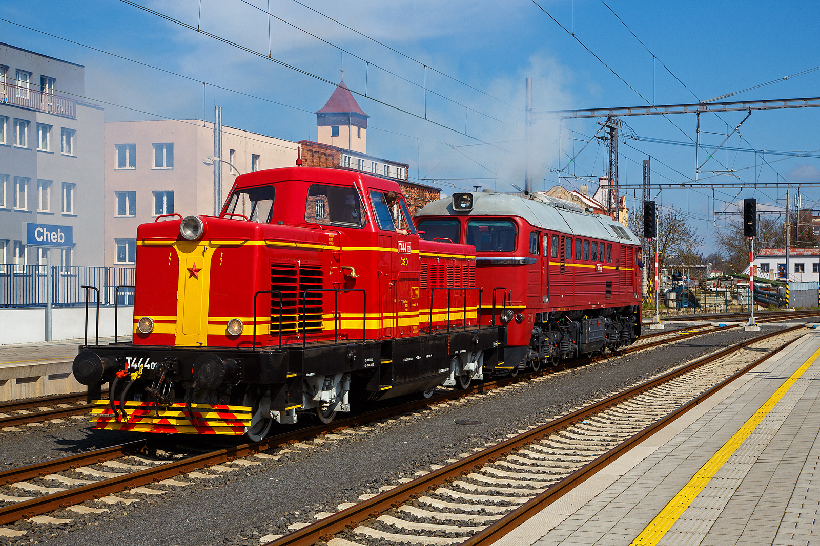 Wie in „alten Zeiten“ der ČSD in der Tschechoslowakei.....
Im Bahnhof Cheb (Eger) rangiert am 21.04.2023, die ex ČSD T679.1600 „Don Cicío“, heutige ČD 781 600-2 (CZ-ČD 90 54 3 781 600-2) mit dem Rotkäppchen („Karkulka“) T 444.030 (heute CZ- ČD 90 54 3 725 030-1) am Haken. Die Dieselabgaswolke kann man am Bild ja sehen, leider nicht den Sound.

Die T 444.030: 
Das Rotkäppchen („Karkulka“) T 444.030 (heute CZ- ČD 90 54 3 725 030-1) wurde 1963 von der Lokfabrik Turčianska strojarne n. p. Martin unter der Fabriknummer  40-00028 gebaut.

Die Baureihe T 444.0 (ab 1988 Baureihe 725) ist/war eine der wenigen dieselhydraulischen Lokomotiven der Tschechoslowakischen Staatsbahn ČSD. Sie wurde entwickelt, um auf Nebenbahnen und im Rangierdienst den Dampfbetrieb zu ersetzen. Die ersten zwei Prototypen wurden 1959 von ČKD in Prag geliefert. Die Serienfertigung erfolgte bei Turčianske strojarne n. p. Martin in der heutigen Slowakei. Insgesamt wurden für die ČSD 113 und für Industriebetriebe 61 Maschinen gebaut und ausgeliefert.

Die wegen des roten Anstriches „Karkulka“ (Rotkäppchen) genannten Lokomotiven besaßen einen Reduktionswandler für den Strecken- und Rangierdienst. Aus Ihnen wurden die spätere Baureihe T 444.1 mit einem Dampfkessel für die Wagenheizung abgeleitet. Dadurch wurde die Brennstoffreserve bei der BR T 444.1 von 4000 l auf 1500 l verkleinert. Die T 444.0 wurden 1988 in die Baureihe 725 umgezeichnet. Da die Lokomotiven keinen Dampfkessel besaßen und der Güterverkehr auf Nebenbahnen kontinuierlich zurückging, konnte bis 1992 auf ihre Dienste verzichtet werden. Etliche Maschinen sind jedoch fahrfähig erhalten geblieben

TECHNISCHE DATEN:
Gebaute Anzahl: 174
Hersteller: ČKD (Entwicklung und Prototypen), Turčianska strojarne n. p. Martin
Baujahre:  1959–1965
Spurweite: 1.435 mm
Achsformel: B´ B´ 
Länge über Puffer: 12.640 mm
Dienstgewicht: 56 t
Treibraddurchmesser:  1.000 mm
Motor: V-12-Zylinder-Viertakt-Dieselmotor vom Typ ČKD K 12 V 170 DR
Motorleistung: 534 kW (726 PS), Nenndrehzahl 1400 U/min
Höchstgeschwindigkeit: 70 km/h Streckengang / 35 km/h Rangiergang
Anfahrzugkraft: 158 kN
Leistungsübertragung: hydrodynamisch