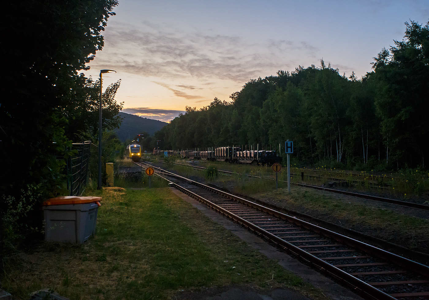 Wie sagt mein Freund immer, „der frühe Vogel fängt den Wurm“, hier war es so. Früh morgens um kurz vor Fünf des 24 Juni 2025 wartet bereits eine MaK G 1206 der WLE - Westfälische Landes-Eisenbahn mit einem Stahlgüterzug, bestehend Schwerlastwagen beladen mit nahtlosen Luppen (Rohrrohlinge), auf Weiterfahrt (Hp 1 oder 2) nach Burbach-Holzhausen zur Salzgitter Mannesmann Precision GmbH. Aber erst darf der entgegenkommende LINT 41 der HLB als RB 96 „Hellertalbahn“ nach Betzdorf/Sieg in den Bahnhof Herdorf einfahren. 