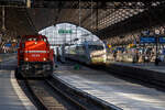 Die RheinCargo DE 84 (98 80 0272 022-1 D-RHC), ex HGK DE 84, eine MaK DE 1002, sowie ein ICE 2 verlassen am 14 Mai 2022 den Hauptbahnhof Köln.