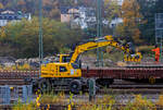 Ein LIEBHERR Zweiwegebagger A 922 Rail Litronic der SPITZKE SE (Großbeeren) mit angebautem Schwellenverlegegerät Typ 159-5 greift sich die nächsten 5 Schwellen von einem