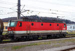 Der „Alpenstaubsauger“ ÖBB 1144 234-2 (A-ÖBB 91 81 1144 234-2) der ÖBB-Produktion GmbH, ex ÖBB 1144 234-0, ex ÖBB 1044 234-1, steht am 02 April 2025 mit einem gemischten Güterzug beim Bahnhof Attnang-Puchheim.

Die Universallok wurde 1991 von der Simmering-Graz-Pauker AG in Graz unter der Fabriknummer 80473 gebaut, die elektrische Ausrüstung ist von der ELIN-UNION AG. Sie wurde als 1044 234-1 an die die ÖBB (Österreichische Bundesbahnen) geliefert. Im März 2003 erfolgte dann der Umbau (Einbau einer Wendezugsteuerung) und die Umzeichnung in die heutige ÖBB 1144 223.

Seit 50 Jahren sind die Lokomotiven der Reihe 1044/1144 unterwegs. Über Jahrzehnte prägten sie das Bild der Bahn. Ihr Lüftergeräusch brachte der Lok mit den Bullaugen den Spitznamen „Alpenstaubsauger“ ein. Sie noch regelmäßig unterwegs, allerdings werden sie immer mehr von moderneren Loks verdrängt.

Im Güterverkehr ist die Lok, die nun als 1144 bezeichnet unterwegs, u.a. in Tirol noch täglich zu sehen, vor allem auf der Strecke von Kufstein bis zum Arlberg. Auch vor Wendezügen versieht sie noch Dienst, diese nicht klimatisierten Züge werden aber zunehmend von Triebwagengarnituren abgelöst. Auch wenn die ehemals stärkste vierachsige Lokomotive der Welt etwa 1.000 Kilowatt weniger Leistung als etwa die modernen Taurus- oder Vectron-Loks hat, heißt das nicht, dass sie sich völlig geschlagen geben muss.

Lok kann ihre Leistung gut auf die Schiene bringen:
Bei einer Lokomotive geht es vor allem darum, ihre Leistung auch auf die Schiene zu bringen und gerade bei widrigen Wetterverhältnissen kann die alte Lok ihre Vorzüge ausspielen, wenn sie etwa am nassen Gleis ein kontrolliertes Durchrutschen der Räder zulässt, das deutlich hörbar ist und auch unter der Bezeichnung „Makroschlupf“ bekannt ist. Das ist aber nur ein Aspekt der technischen Meisterleistung, die hinter dieser Lok steckt.

Entwickelt wurde die Lok von österreichischen Firmen, es wurde aber auch teilweise die Technik einer schwedischen Lok (der Rc2) übernommen, die in Österreich als Reihe 1043 im Dienst stand und bereits eine stufenlose Steuerung der Zugkraft aufwies. Die Versuche mit dieser Lok waren sehr positiv ausgefallen. Diese sogenannte „Thyristorsteuerung“ wurde auch bei der 1044 übernommen, allerdings war die 1044 für höhere Geschwindigkeiten und deutlich mehr Leistung ausgelegt. Damit konnte mit dieser Lok leistungsmäßig die Grenze einer Stufensteuerung überwunden werden.

Die Thyristoren werden mit Öl gekühlt, „diese möchten sehr gut gekühlt werden, weil da einfach viel Leistung erzeugt wird“. Aufgrund dieser Luftdurchsatzmenge ist dann das Heulen entstanden, das der Lok ihren Spitznamen „Alpenstaubsauger“ einbrachte.

Ab 1978 in Serie gefertigt:
Zuerst rief man die Baureihe 1044 mit zwei Prototypen ins Leben. Der erste Prototyp, die 1044.01, war ab 1974 im Einsatz. Ab 1978 wurden die Serienloks in Dienst gestellt. Die 1044 war eine klassische Universallokomotive, die für alle Züge eingesetzt werden konnte. Von Kinderkrankheiten blieb auch diese Reihe nicht verschont, Radreifenbrüche und vor allem Ausfälle durch Flugschnee machten Änderungen bei der Konstruktion notwendig.

Aus der 1044 wurde die 1144:
Letztlich bewährten sich die Lokomotiven aber sehr gut und sie wurden für Jahrzehnte zum Paradepferd der ÖBB. Die Lokomotiven mit einer Leistung von bis zu 5.400 Kilowatt waren für 160 km/h zugelassen. Mit dem Umbau zur Tauglichkeit für Wendezugbetrieb mit Steuerwagen wurde aus der 1044 die 1144. Zuletzt im Jahr 1995 wurden nochmals 36 Stück der Lokomotive bestellt, ehe im Jahr 2000 mit der „Taurus“ ein Nachfolger den Dienst antrat.

Ein einheitliches Erscheinungsbild haben die Loks bis heute nicht. Sie sind in verschiedenen Lackierungen unterwegs und ein Blick auf die Lüftungsgitter auf der Dachkante verrät eine große Vielfalt, hier gibt es niedrige Gitter, hohe Gitter, gemischte Varianten, Gitter mit Schalldämpfern sowie Gitter ohne Schalldämpfung. Die erste Prototyplokomotive (1044.01) wurde zu einer Schnellfahrlokomotive umgebaut, die für 220 km/h zugelassen ist und die Bezeichnung 1044.501 erhielt. Insgesamt wurden 217 Stück der 84 Tonnen schweren und 16,1 Meter langen Lok gebaut.

Die Bremsenergie wird in Wärme statt Strom umgewandelt
Seit dem Jahr 2018 werden immer wieder Maschinen der Reihe 1144 ausgemustert. Ein Nachteil gegenüber modernen Maschinen ist, dass sie die beim elektrischen Bremsen gewonnene Energie in Wärme umwandelt und nicht als Strom ins Netz rückspeisen kann.

Mittlerweile veraltete Steuerungstechnik
Die Thyristortechnik ist inzwischen „veraltet“. So erzeugt diese Technik auch eine gewisse „Blindleistung“, welche das Stromnetz geschwächt. Das ist kein großes Problem, hat es aber etwas herausfordernder gemacht. Eine Prognose, wie lange die 1144 noch im regulären Einsatz steht ist noch unklar. Das entscheide der Fahrzeugeigentümer. Aber mit der Möglichkeit, Strom in die Fahrleitung zurückzuspeisen, erspart man sich schon sehr viel Geld. Somit haben modernerer Loks eine höhere Wirtschaftlichkeit.

TECHNISCHE DATEN:
Gebaute Anzahl: 217
Baujahre: 1976 bis 1995
Hersteller (mechanisch): SGP Simmering-Graz-Pauker AG (Graz)
Hersteller (elektrisch): BBC (ABB), ELIN, Siemens Wien
Spurweite:  1.435 mm (Normalspur)
Achsformel:  Bo’Bo’
Länge über Puffer:  16.100 mm
Begrenzungslinie: UIC 505-1
Drehzapfenabstand: 8.000 mm
Achsabstand in Drehgestell: 2.900 mm
Raddurchmesser:  1.300 mm (neu) / 1.210 mm (abgenutzt)
Kleinster bef. Halbmesser (V  max= 10 km/h): 120 m 
Dienstgewicht: 84 t
Höchstgeschwindigkeit: 160 km/h (1044.501, ex 1044.01 nach Umbau 220 km/h)
Stundenleistung: 5.280 kW
Dauerleistung: 5.000 kW
Anfahrzugkraft: 340 kN
Dauerzugkraft:  208,9 kN
Stromsysteme: 15kV/16,7Hz AC
Antriebsart: Thyristor-Gleichrichter, Mischstrom-Fahrmotoren mit
Reihenschluß- (45 %) und Fremderregung (55 %), BBC- Federantrieb
Anzahl der Fahrmotoren: 4
Dynamisches Bremssystem: Elektrodynamische Gleichstrom-Widerstandsbremse
Nenn- / Höchstleistung der dynamischen Bremse:  2.400 / 3.720 kW
Max. Bremskraft der dynamischen Bremse: 115 kN
Bremsbauart: On-GPR-E m Z, ep. / NBÜ nach „DB-Norm“
Zugheizung: 800 kVA

Quellen: ÖBB, ÖBB-Produktion GmbH und Wikipedia
